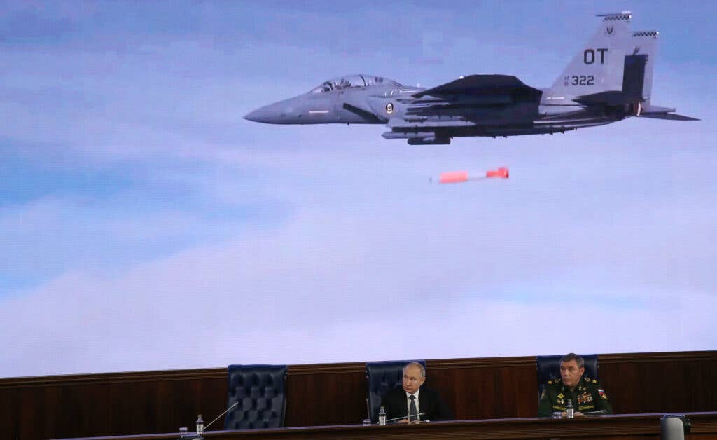 Russian President Vladimir Putin (left) and Chief Commander of General Staff Valery Gerasimov watch a clip with a U.S. Air Force F-15E Strike Eagle dropping an inert B61-12, during an annual meeting with top military officials at the Extended Board of the Ministry of Defense in Moscow, December 24, 2019. <em>Mikhail Svetlov/Getty Images</em>