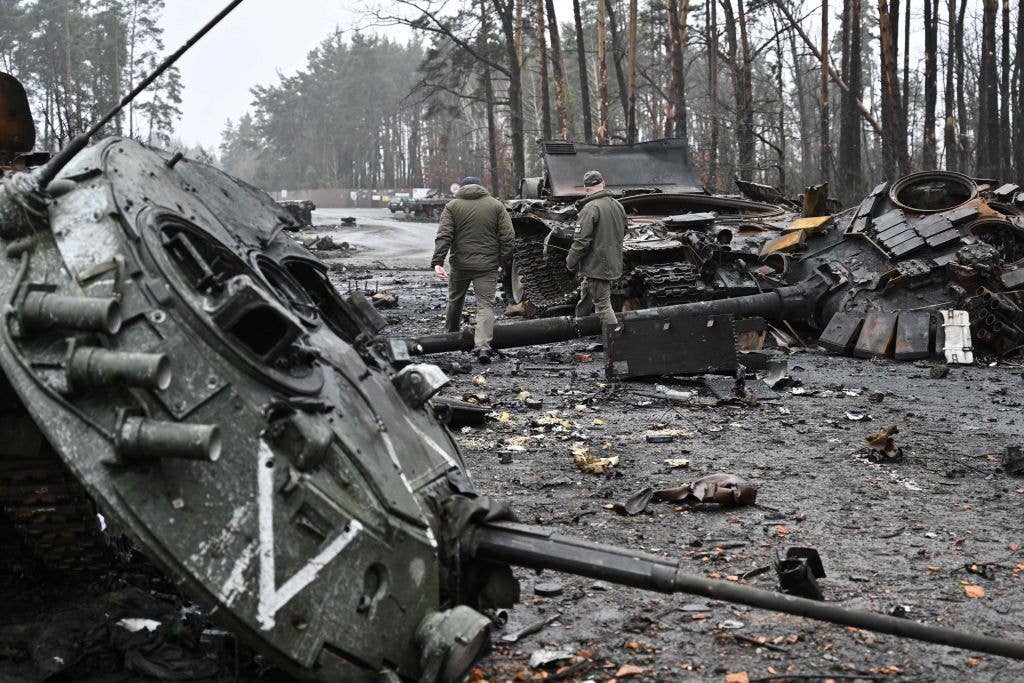 Ukrainian servicemen walk next to destroyed Russian tanks and armored personnel carriers in Dmytrivka village, west of Kyiv, on April 2, 2022. (Photo by GENYA SAVILOV/AFP via Getty Images)