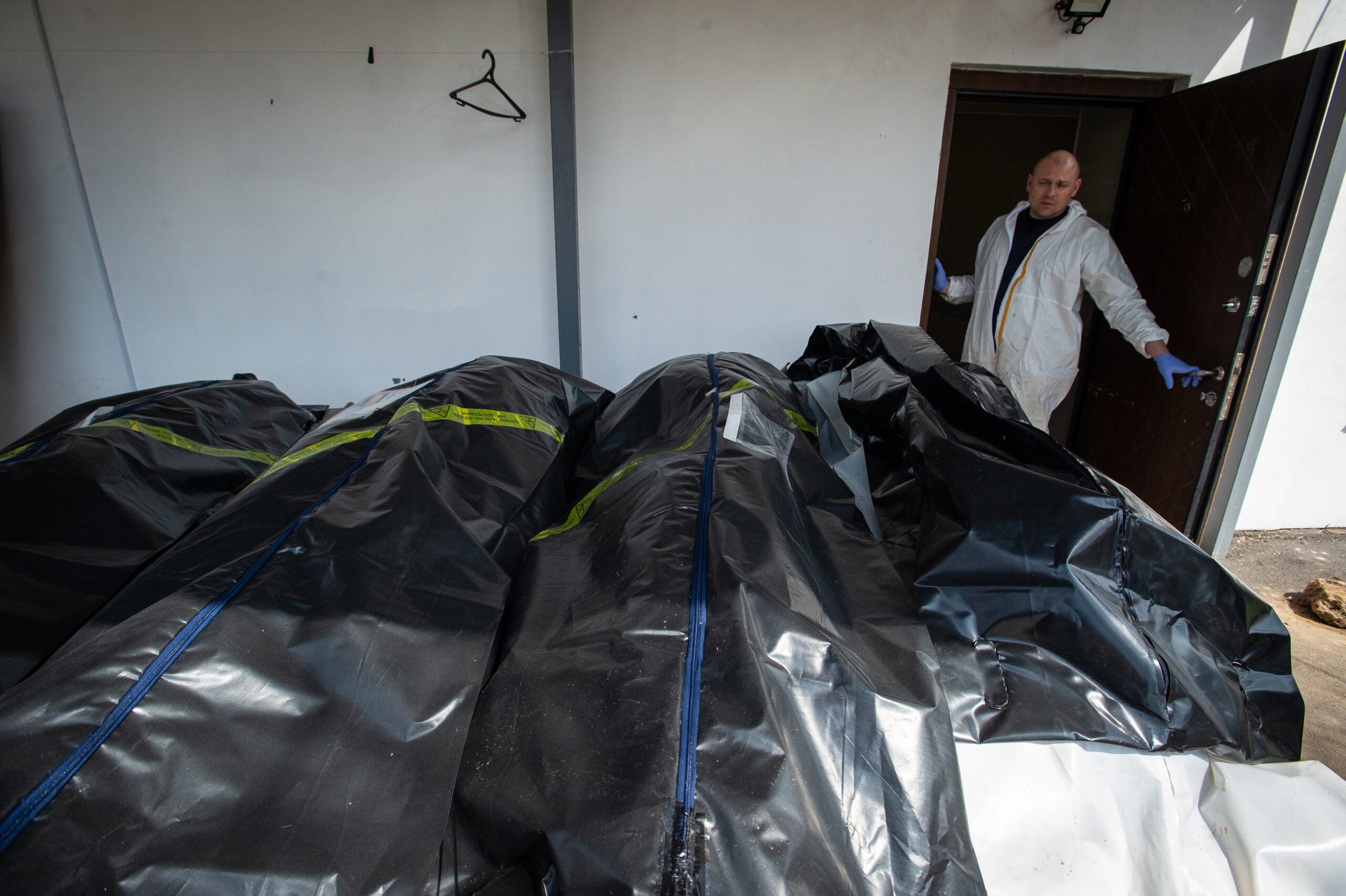 BUCHA, UKRAINE - APRIL 23: (EDITORS NOTE: Image contains graphic content) Ukrainian morticians look at body bags full of corpses, as a morgue overflows with victims who died during the Russian military presence in the Kyiv suburb of Bucha, Ukraine, on April 23, 2022. Ukrainian officials and volunteers are beginning the work of identifying the dead and gathering evidence for war crimes accusations, and say that more than 1,000 civilians lost their lives when Russian troops occupied districts northwest of the capital for weeks after a February 24 invasion. (Photo by Scott Peterson/Getty Images)