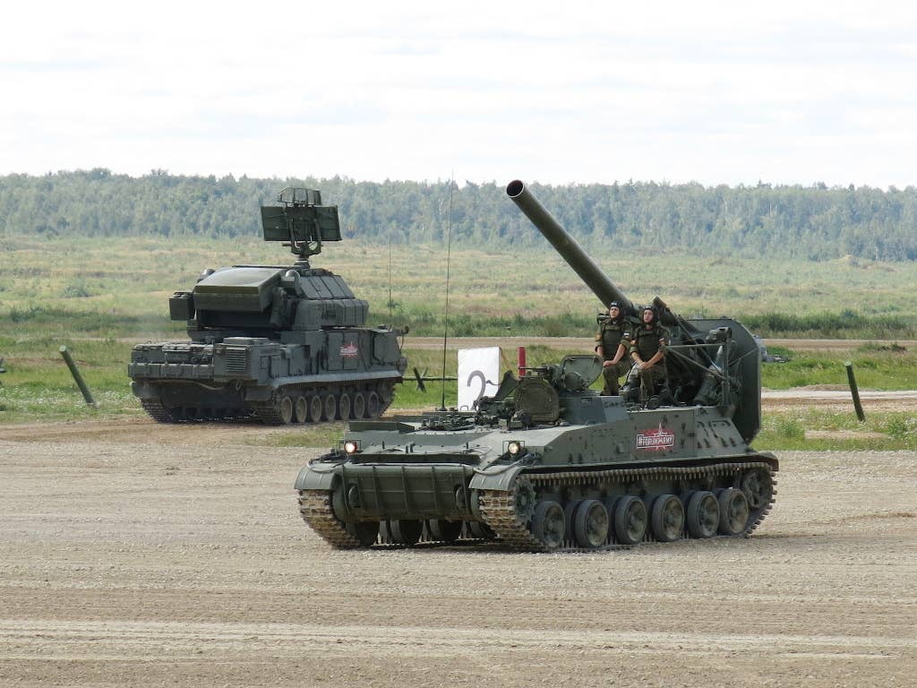 A 2S4 self-propelled mortar in the foreground, with a Tor-series surface-to-air missile system in the background. <em>Wikimedia Commons</em>