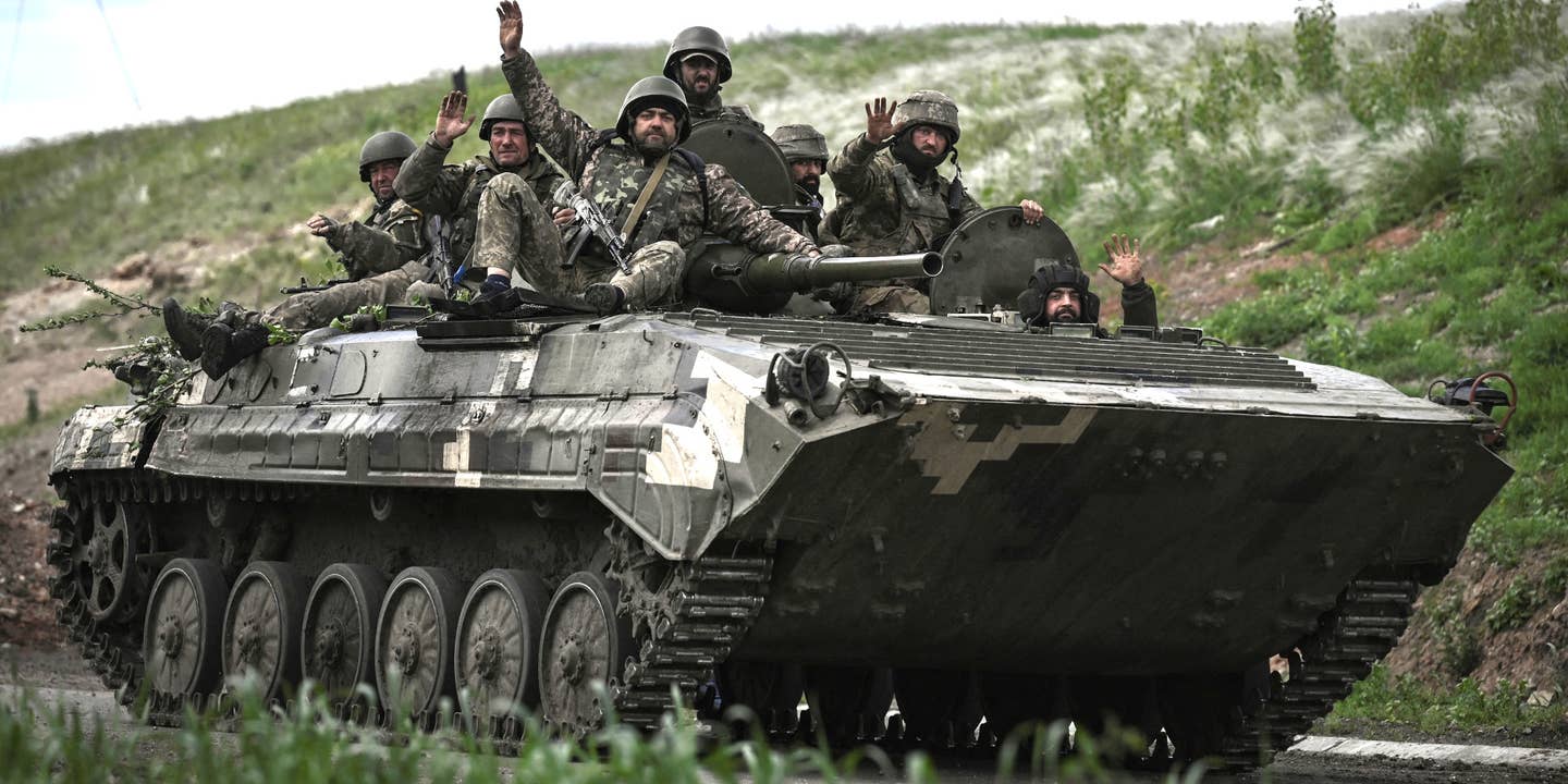 Ukrainian servicemen wave as they move with an armored vehicle toward the frontline at a checkpoint near the city of Lysychansk in the eastern Ukranian region of Donbas, on May 23, 2022, amid Russian invasion of Ukraine.