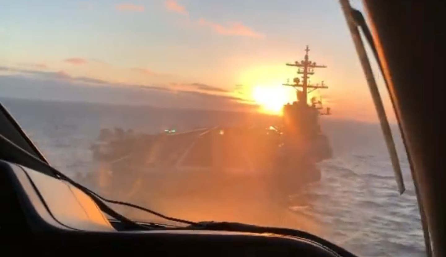 A cockpit view from the Phenom camera ship just before it passes over the fantail with the setting sun in the distance. See the meatball on the left side of the deck. <em>@k2_larosa/Kevin LaRosa. </em>