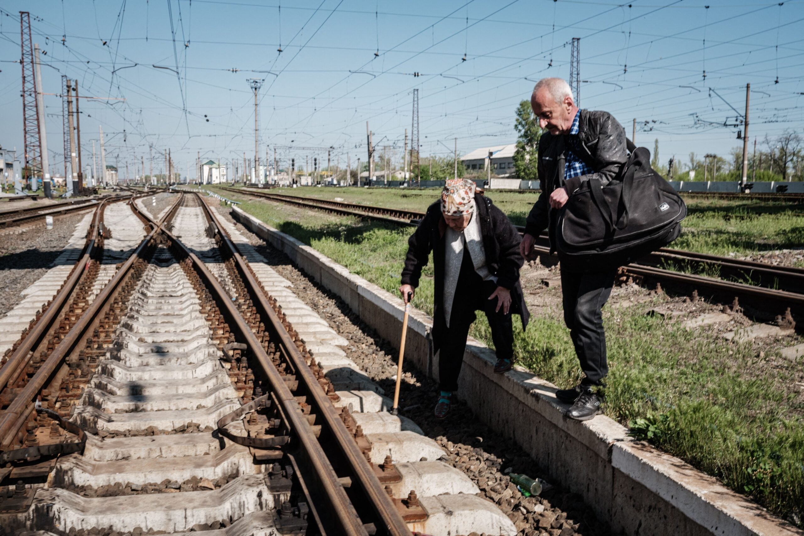 An elderly couple cross railroad tracks instead of using a flyover to get to the bus stop ahead of evacuation from Lyman, eastern Ukraine, on April 28, 2022, amid the Russian invasion of Ukraine. (Photo by Yasuyoshi CHIBA / AFP) (Photo by YASUYOSHI CHIBA/AFP via Getty Images)