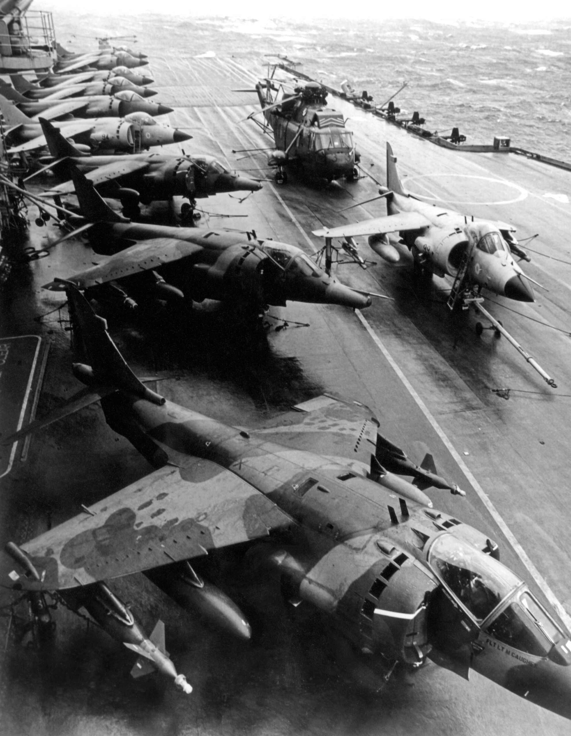 Harrier GR.3 aircraft of 1 Squadron parked alongside Royal Navy Sea Harriers and a Sea King helicopter on the flight deck of HMS Hermes on 19 May 1982, the day that 1 Squadron joined with Hermes in the South Atlantic.

The Sea Harrier FRS.1 differed from the RAF's  GR.3 in having extensive corrosion-proofing, a cockpit that was raised to provide the pilot with a better view, and a multi-mode radar called Blue Fox, which could search for targets in the air or on the sea. 

*Some of these images have had some dodging and burning done and have been retouched to remove detritus and dust and scratch marks only*