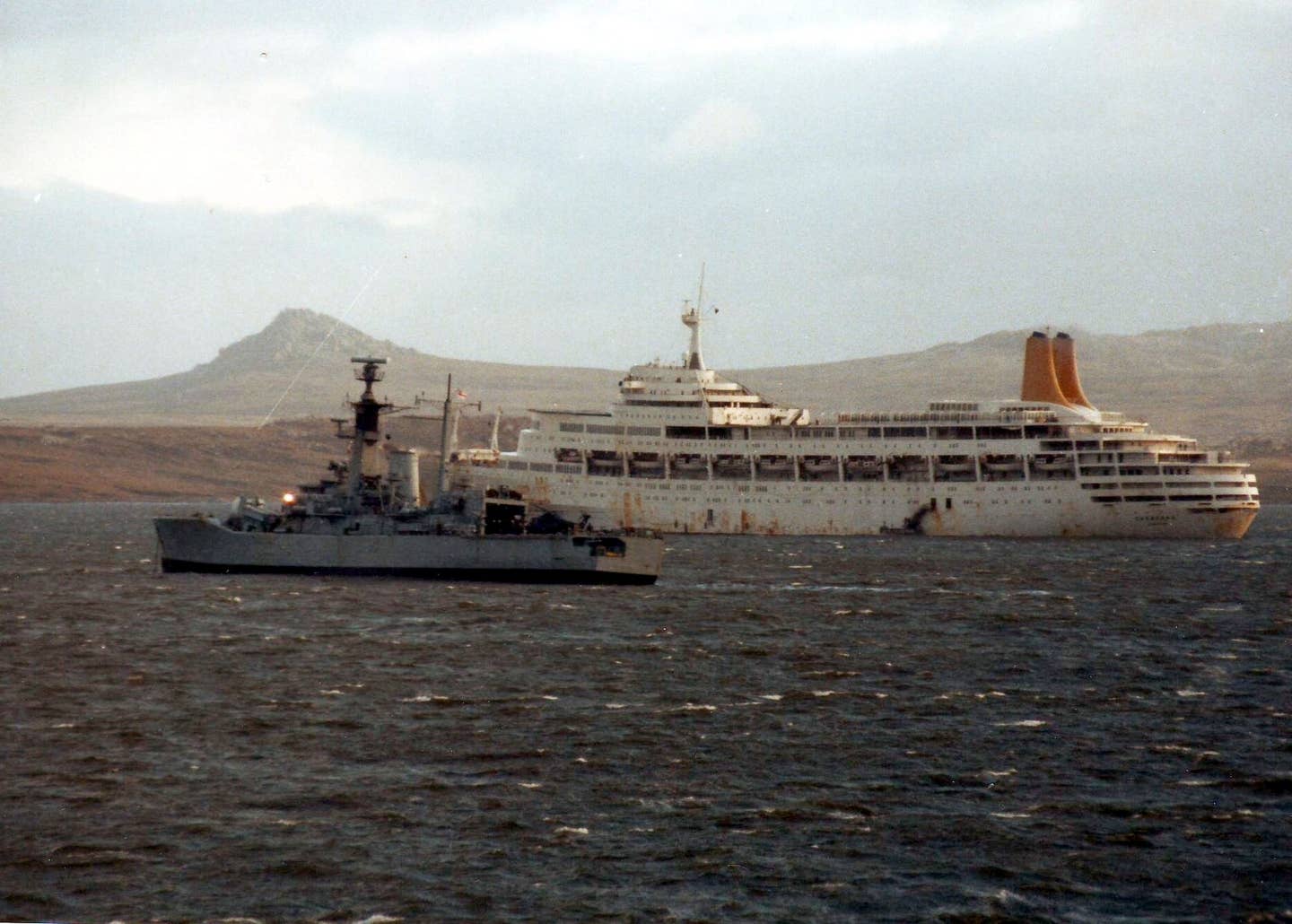 SS&nbsp;<em>Canberra</em>&nbsp;(background) and HMS&nbsp;<em>Andromeda</em>&nbsp;outside Port Stanley, Falkland Islands, just after the surrender of Argentine forces on June 14, 1982. The <em>Canberra</em> was the hospital ship from which Splash escaped via a door in the hull to rejoin his unit. <em>Ken Griffiths/Wikimedia Commons</em>