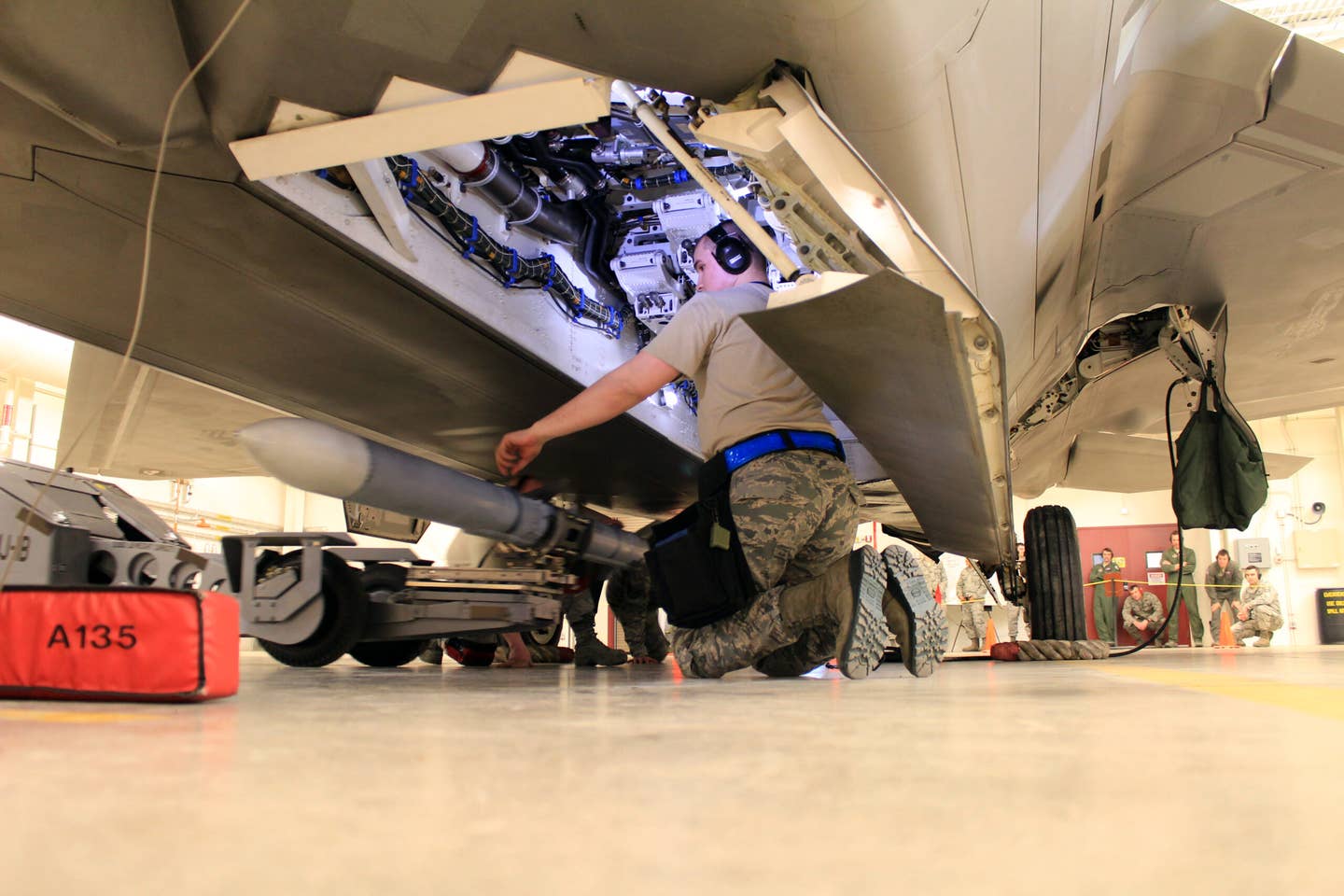 A maintainer prepares to guide an AIM-120 AMRAAM missile into place in the weapons bay of an F-22. <em>U.S. Air Force/Tech. Sgt. Dana Rosso</em>