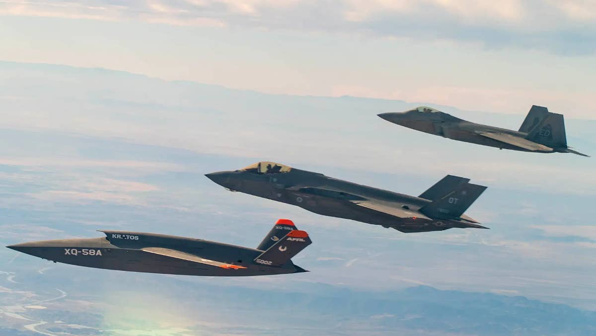 An XQ-58A Valkyrie unmanned aircraft, examples of which have<em> been used to support the Skyborg program, at left flies together with an F-35 Joint Strike</em> Fighter, at center, and an F-22 Raptor, at right. <em>USAF</em>