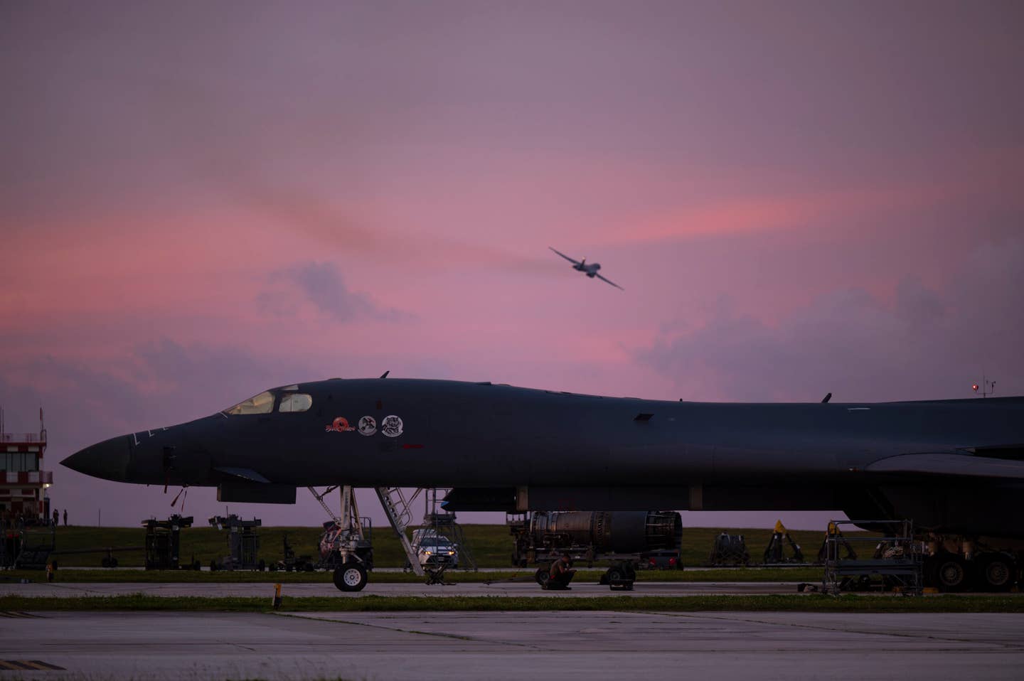 A 34th Expeditionary Bomb Squadron B-1B flies over another Lancer on the ground at Andersen Air Force Base, June 12, 2022. <em>U.S. Air Force photo by Master Sgt. Nicholas Priest</em>