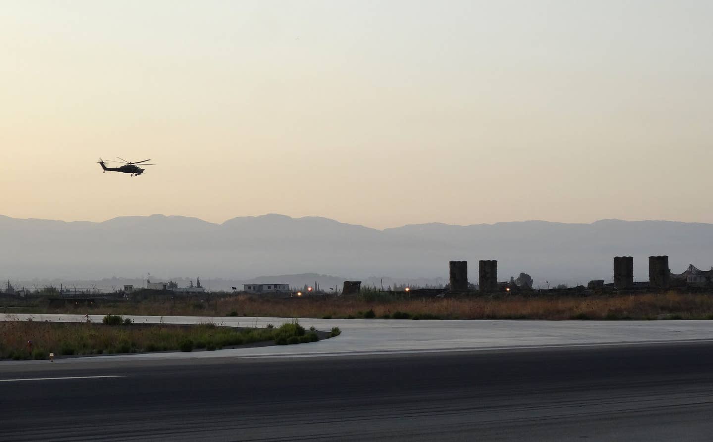 Russian S-300 systems defend Khmeimim Air Base in northwest Syria in September 2017 while a Mi-28N attack helicopter flies overhead. <em>MARIA ANTONOVA/AFP via Getty Images</em>