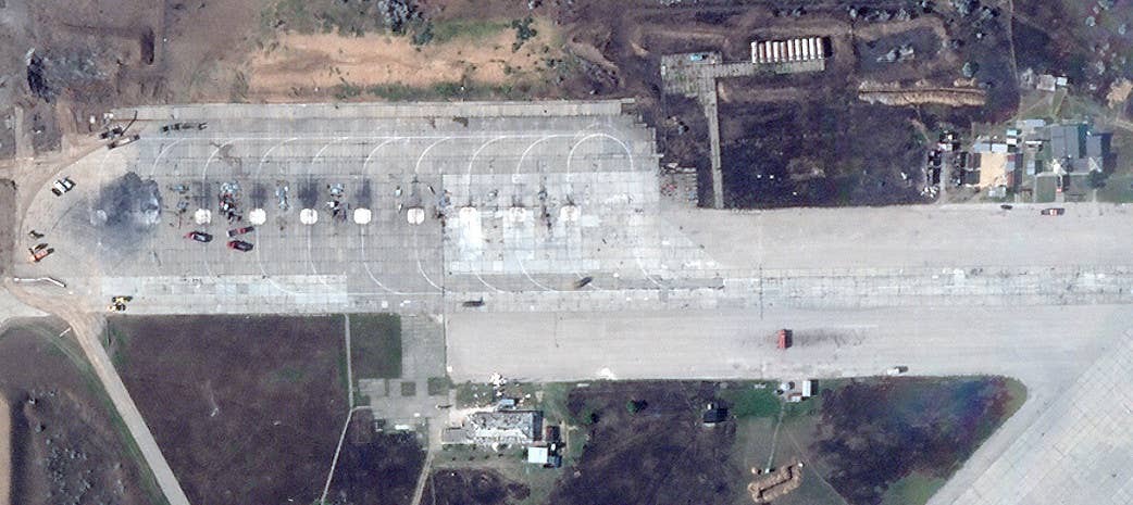 A close-up of the ramp at the southwestern end of Saki Air Base showing the remains of multiple aircraft. Fire trucks and other vehicles can be seen, as well. There is visible damage to the structures to the immediate south and east, too. <em>PHOTO © 2022 PLANET LABS INC. ALL RIGHTS RESERVED. REPRINTED BY PERMISSION</em>