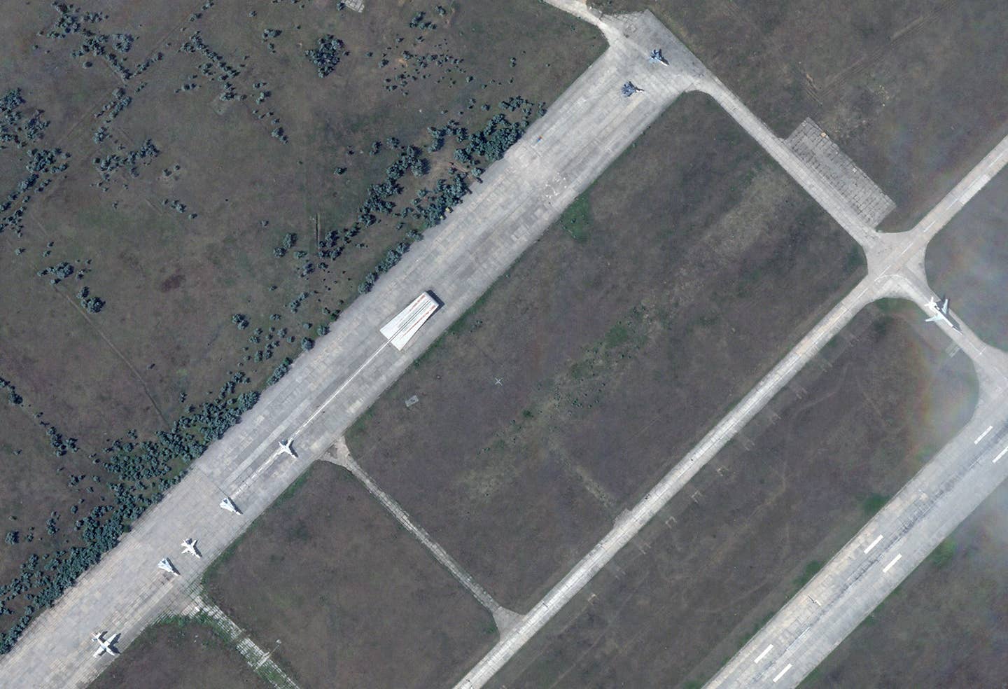 Various aircraft at the northeastern end of Saki Air Base, including the Tu-134UBL at far right, all of which appear at least superficially to be undamaged. Also visible here is a ski jump used in the past for land-based training and testing related to operations from Russia's lone aircraft carrier, the short take-off, barrier-arrested recovery (STOBAR) configured <em>Admiral Kuznetsov</em>. <em>PHOTO © 2022 PLANET LABS INC. ALL RIGHTS RESERVED. REPRINTED BY PERMISSION</em>