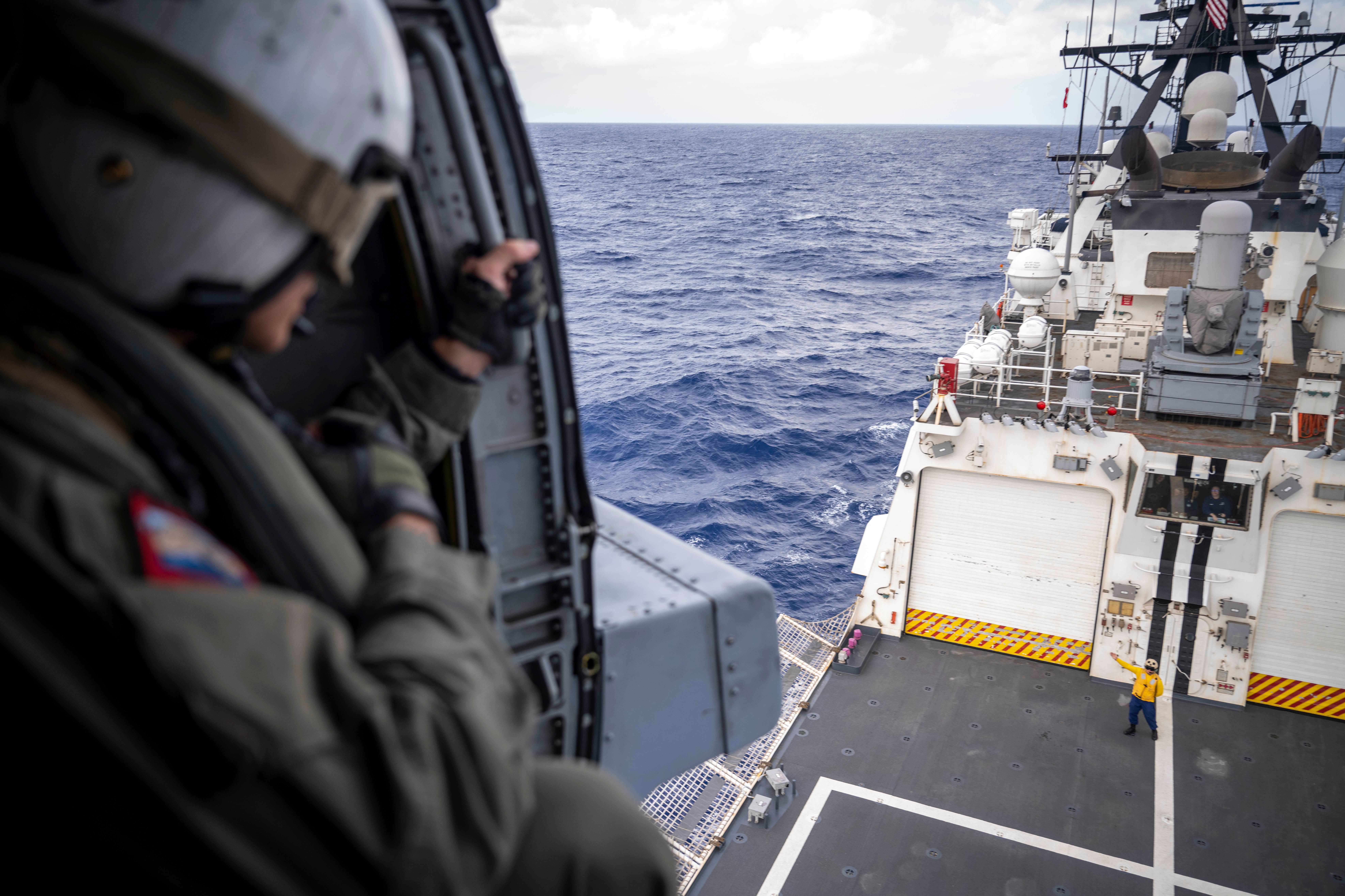 PACIFIC OCEAN (July 30, 2022) U.S. Navy Petty Officer 1st Class Humberto Alba, a naval aircrewman tactical-helicopter, attached to Helicopter Maritime Strike Squadron (HSM) 37, deployed on U.S. Coast Guard Legend-class cutter USCGC Midgett (WMSL 757), looks down at a USCGC crewmember after taking off during flight operations during Rim of the Pacific (RIMPAC) 2022. Twenty-six nations, 38 ships, three submarines, more than 170 aircraft and 25,000 personnel are participating in RIMPAC from June 29 to Aug. 4 in and around the Hawaiian Islands and Southern California. The world's largest international maritime exercise, RIMPAC provides a unique training opportunity while fostering and sustaining cooperative relationships among participants critical to ensuring the safety of sea lanes and security on the world's oceans. RIMPAC 2022 is the 28th exercise in the series that began in 1971. (U.S. Coast Guard photo by Petty Officer 3rd Class Taylor Bacon)