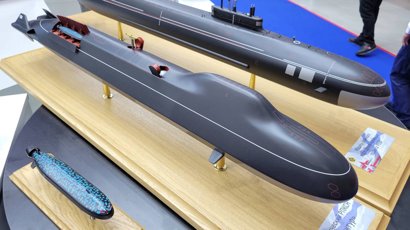 A model of a Russian submarine concept called Arktur, at center, with another one showing an unmanned underwater vehicle design known as Surrogat-V in front of it. A model of a Russian Navy Borei-A class ballistic missile submarine is seen behind.