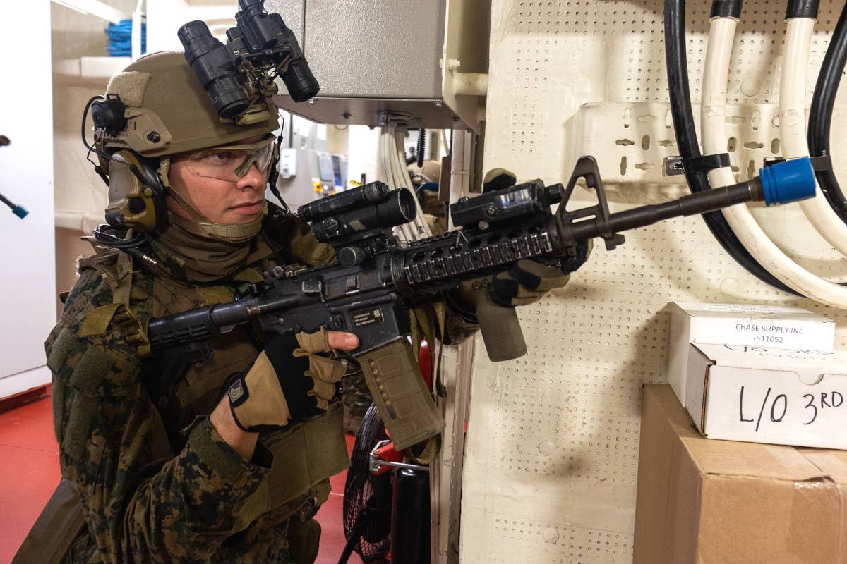 A reconnaissance Marine with a standard M4 carbine maneuvers through a ship during a training exercise. A shorter weapon could be useful in closer-quarters situations like this. <em>USMC / Lance Cpl. Christopher W. England</em>