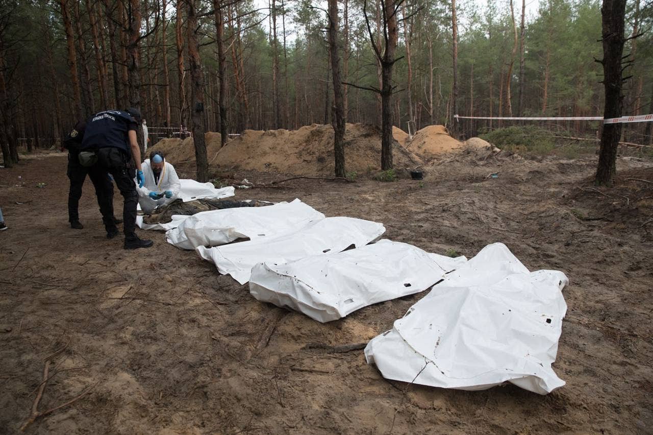 Ukrainian investigators examining bodies unearthed in Izyum. (Volodymyr Zelensky Telegram photo)