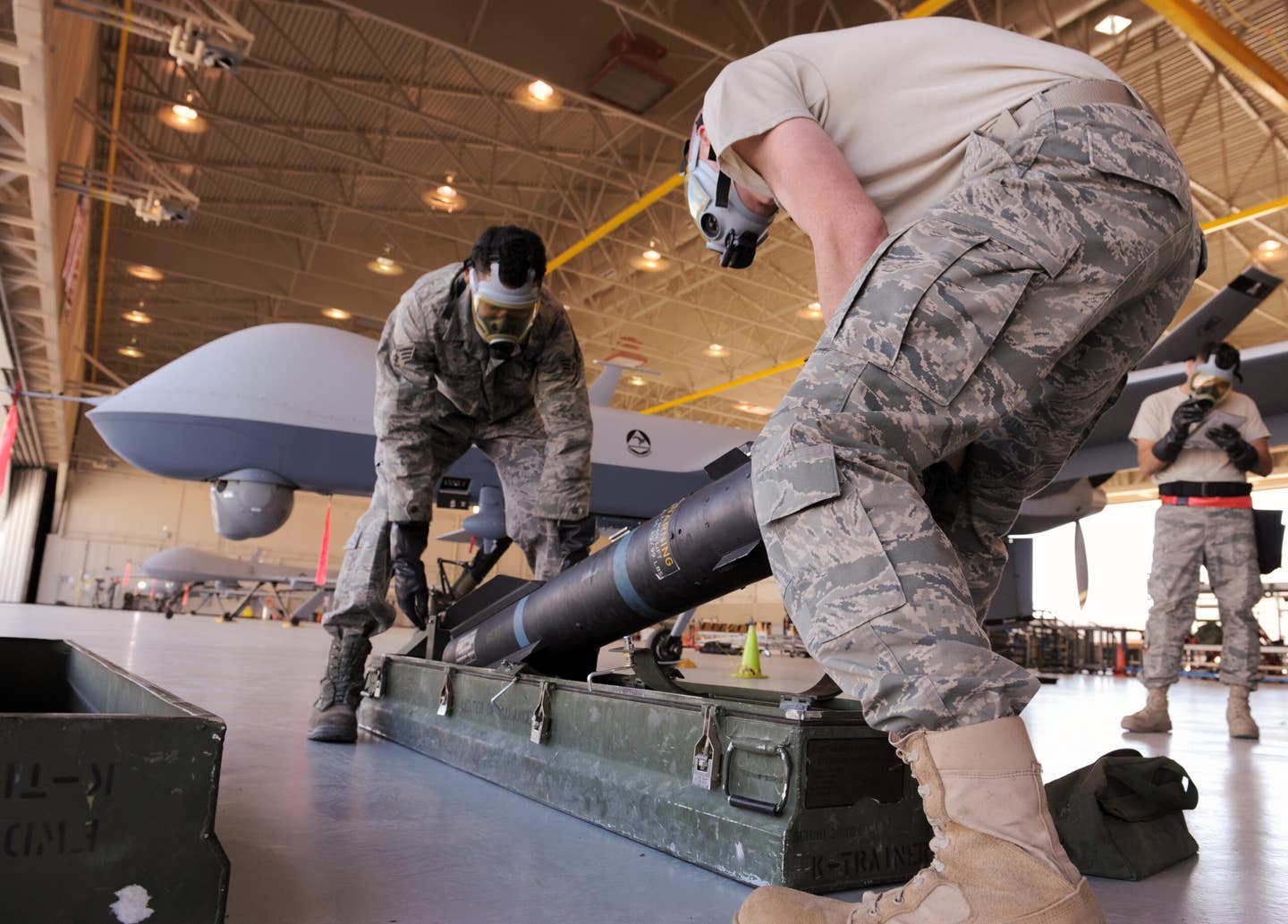 U.S. Air Force ground crew prepare to load an AGM-114 Hellfire air-to-ground missile onto an MQ-9 Reaper during weapons load training at Creech Air Force Base, Nevada. <em>U.S. Air Force photo/Senior Airman Larry E. Reid Jr.</em>