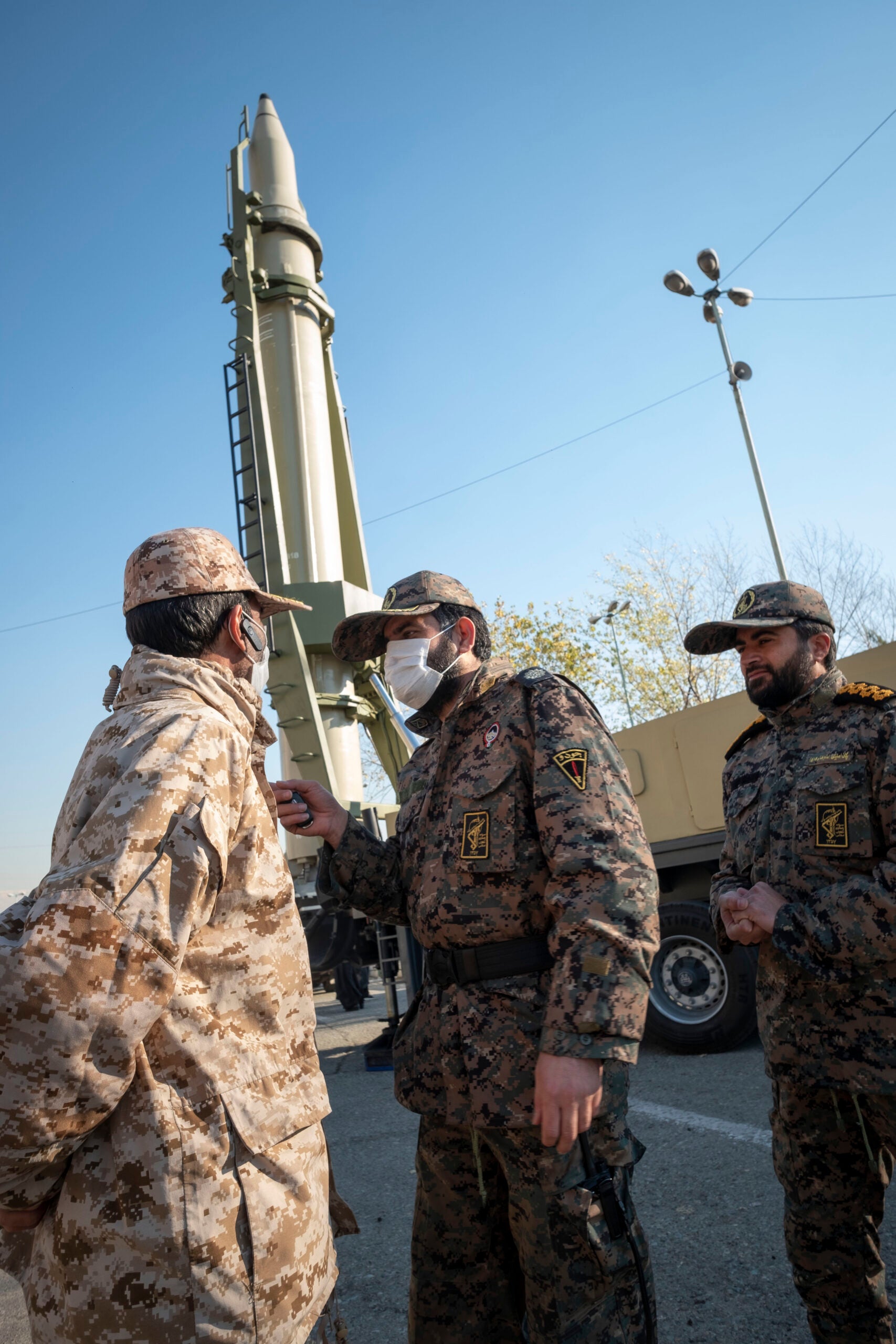 Islamic Revolutionary Guard Corps (IRGC) military personnel talk to each other as an Iranian Qiam short-range surface-to-surface ballistic missile is displayed in a military exhibition to mark the anniversary of an Iran missile attack on the U.S. Ain al-Assad airbase in Iraq in revenge for killing the former commander of the IRGC Quds Force, General Qasem Soleimani, at the Imam Khomeini Grand Mosque in downtown Tehran on January 7, 2022. Irans Aerospace Force of the Islamic Revolutionary Guard Corps (IRGC) has attacked the U.S. military airbase in revenge for killing the former commander of the IRGC Quds Force, General Qasem Soleimani, who has been killed in a U.S. drone attack in Baghdad International Airport in Iraq in 2020, with surface-to-Surface missiles.  (Photo by Morteza Nikoubazl/NurPhoto via Getty Images)