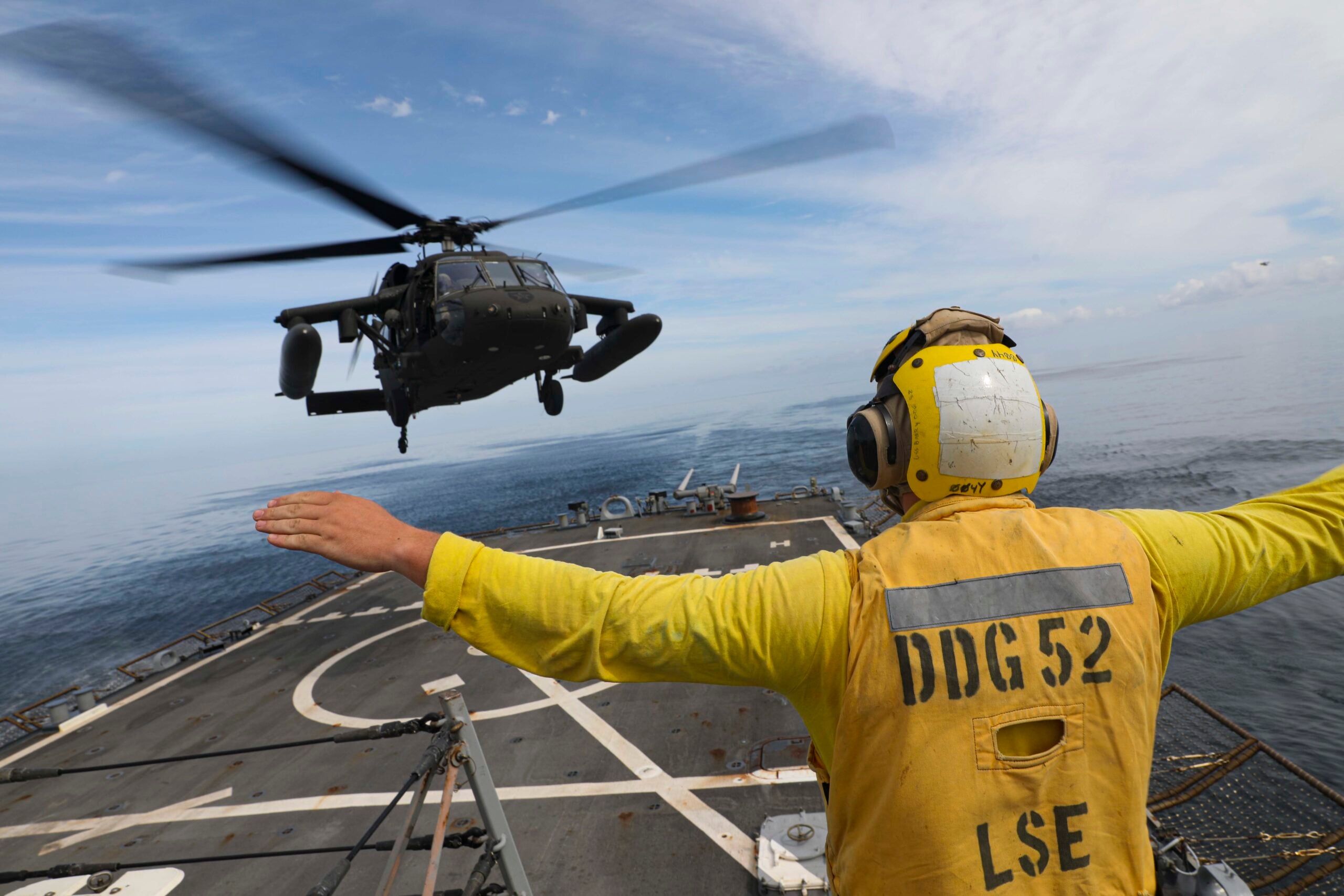 WATERS OFF THE COAST OF THE KOREAN PENINSULA (Sept. 26, 2022) – Seaman Evan Sand, from Annandale, Minnesota, signals a UH-60M Black Hawk helicopter assigned to the Army’s 2nd Combat Aviation Brigade as it lands on the flight deck aboard Arleigh Burke-class guided-missile destroyer USS Barry (DDG 52). Barry, as part of the Ronald Reagan Carrier Strike Group (CSG), is participating with the Republic of Korea (ROK) Navy in Maritime Counter Special Operations Exercise (MCSOFEX) to strengthen interoperability and training. The U.S. routinely conducts CSG operations in the waters around the Republic of Korea to exercise maritime maneuvers, strengthen the U.S.-ROK alliance and improve regional security. (U.S. Navy photo by Mass Communication Specialist 1st Class Greg Johnson)