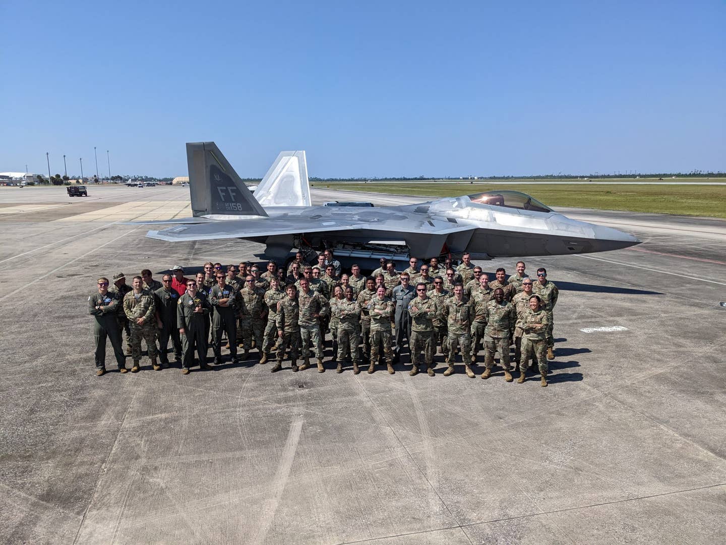Members from the 94th Fighter Squadron and 94th Fighter Generation Squadron pose for a photo during Weapons System Evaluation Program 22.12 at Tyndall Air Force Base, Florida, in September 2022. The units employed 28 air-to-air missiles, breaking the record for the most AAMs loaded and successfully fired by F-22s. <em>U.S. Air Force</em>