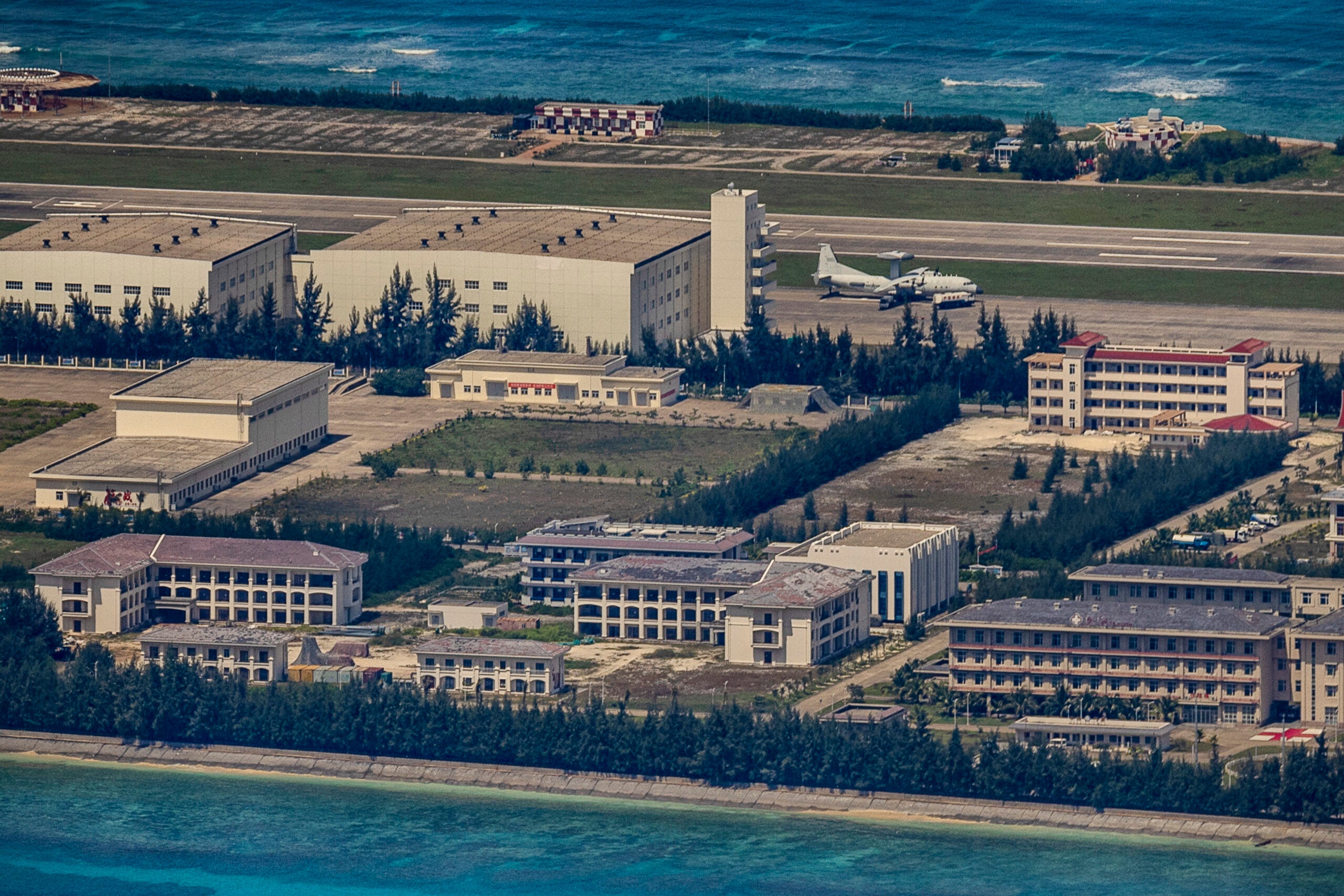 SPRATLY ISLANDS, AT SEA - OCTOBER 25: A plane sits on an airfield next to buildings and structures on the artificial island built by China in Fiery Cross Reef on October 25, 2022 in Spratly Islands, South China Sea. China has progressively asserted its claim of ownership over disputed islands in the South China Sea by artificially increasing the size of islands, creating new islands and building ports, military outposts and airstrips. The South China sea is an important trade route and is of significant interest as geopolitical tensions remain high in the region. (Photo by Ezra Acayan/Getty Images)