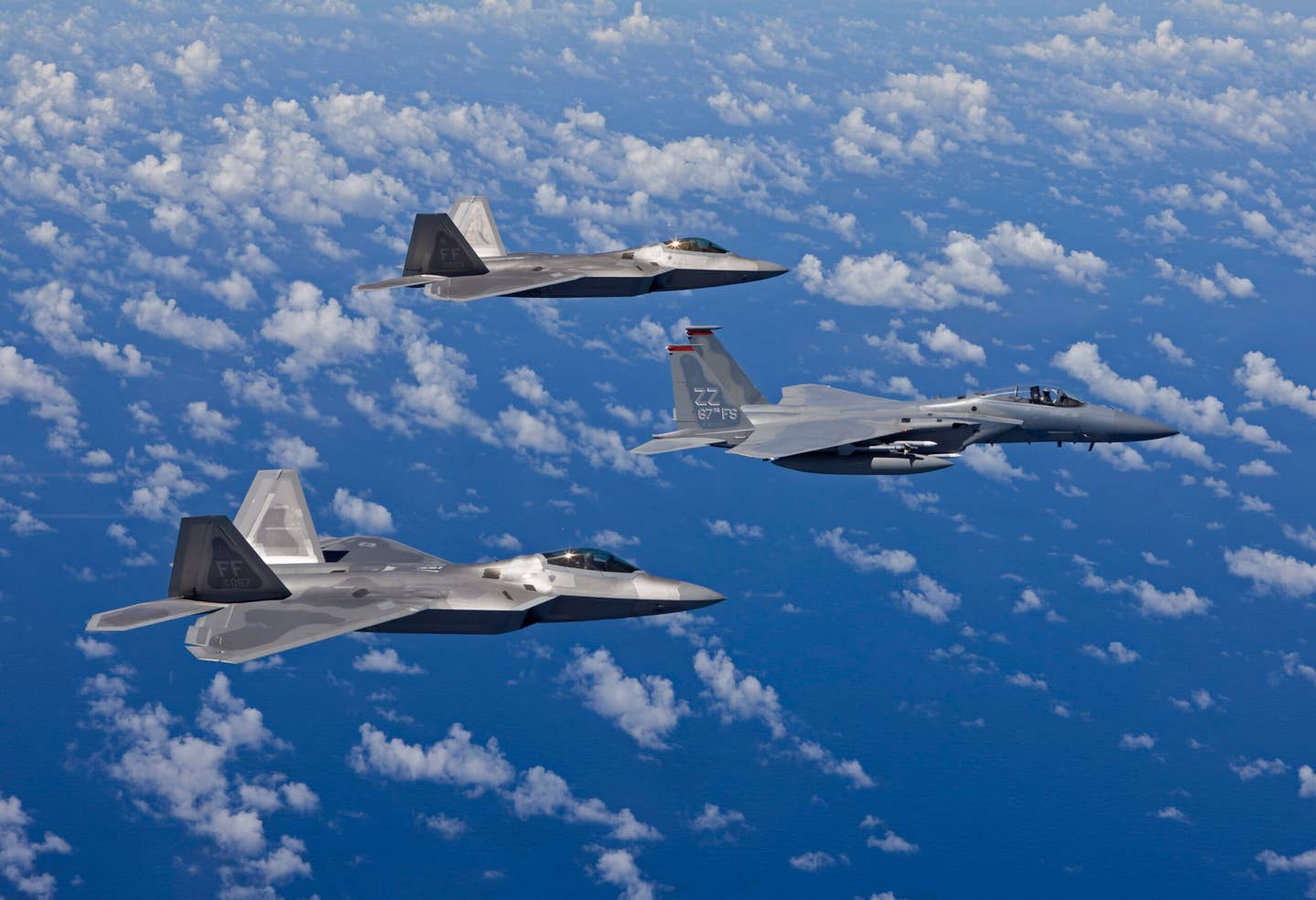 An F-15C from the 67th Fighter Squadron at Kadena Air Base, Okinawa, flies over the Pacific Ocean in formation with two F-22s from Langley Air Force Base, Virginia, during a training mission. <em>Getty Images</em>