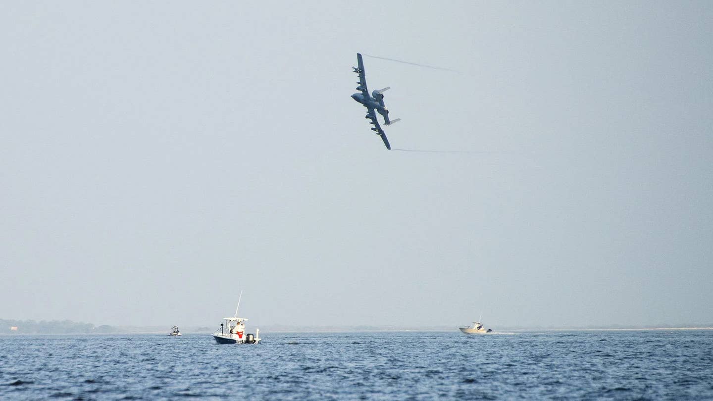An A-10 flies over small boats playing the role of a hostile boat swarm during a training exercise in 2017. <em>USAF</em>
