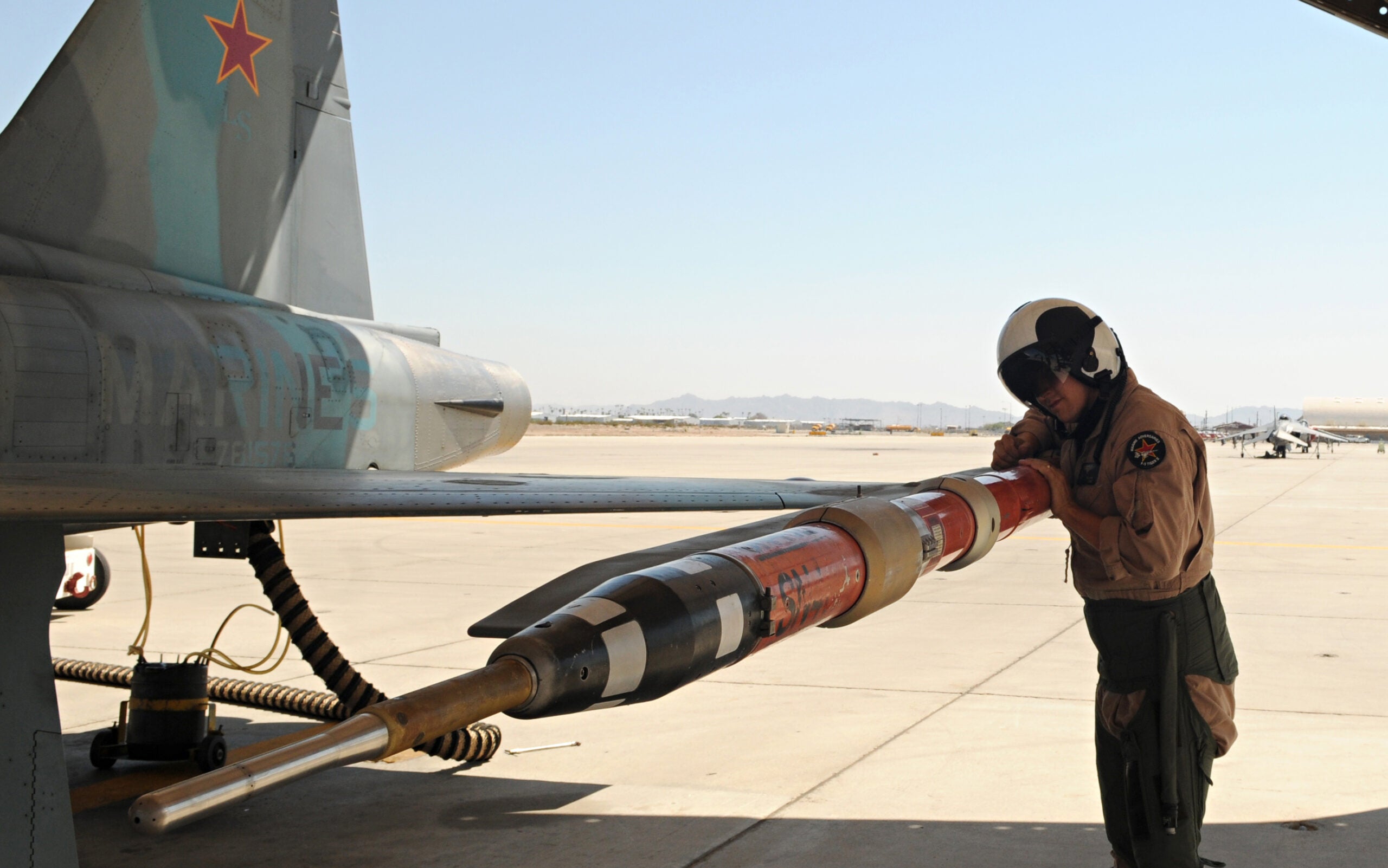 Maj. Chris Holloway, Marine Fighter Training Squadron 401 pilot, checks the placement of a tactical combat training system pod on an F-5E Tiger aircraft prior to takeoff at the Marine Corps Air Station in Yuma, Ariz., Aug. 13, 2010. The pod allows the TCTS to track the movement and weapons systems of the aircraft while taking part in training exercises.