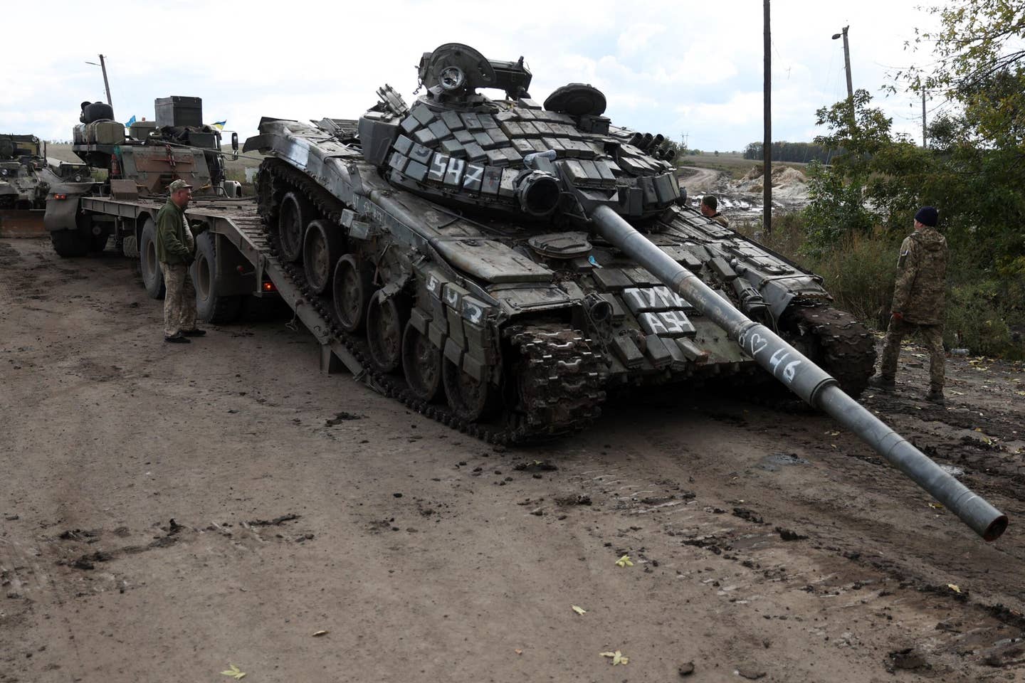 A captured Russian T-72 tank is loaded on a truck by Ukrainian soldiers outside the town of Izyum on Sept. 24. (Photo by ANATOLII STEPANOV/AFP via Getty Images)