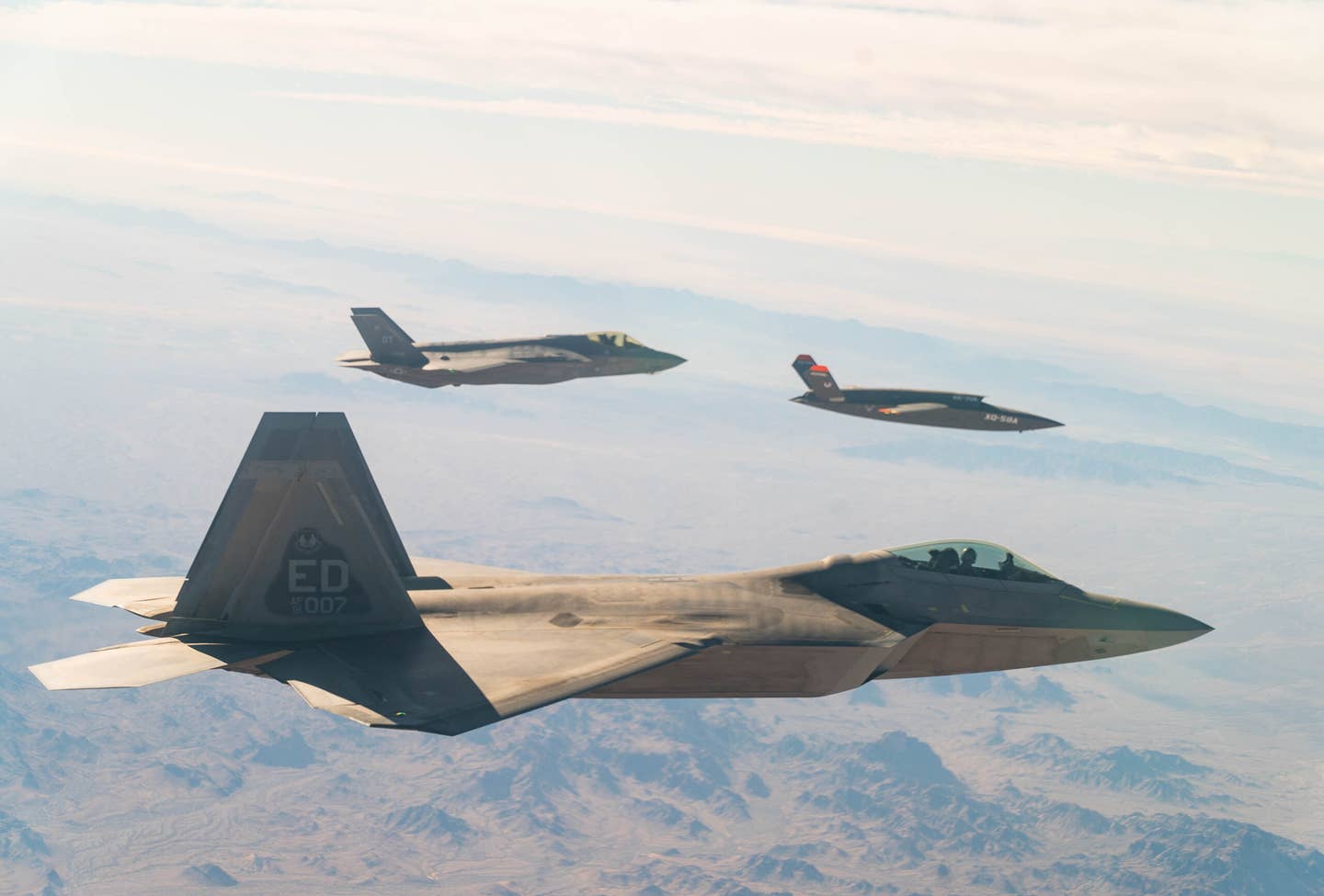 A U.S. Air Force F-22 Raptor and F-35A Lightning II fly in formation with the XQ-58A Valkyrie over the U.S. Army Yuma Proving Ground testing range, Ariz., during a series of tests Dec. 9, 2020. <em>Credit: U.S. Air Force photo by Tech. Sgt. James Cason</em>