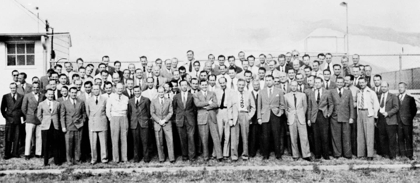 Team of 104 German rocket scientists at Fort Bliss, Texas; 1946. Wernher von Braun is to the right of center, grey jacket, black trousers, white handkerchief, hand in his pocket. <em>Unknown photographer/Wikimedia Commons.</em>
