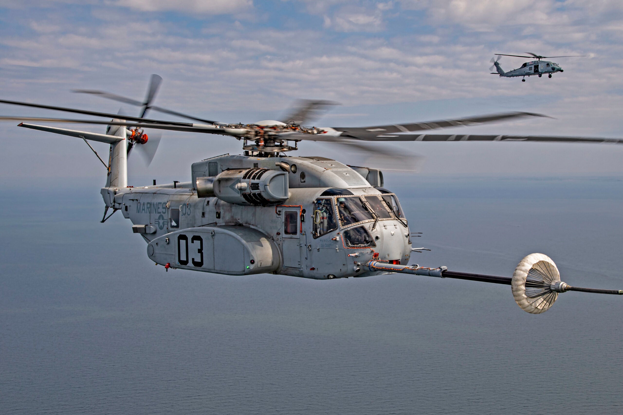 The CH-53K King Stallion successfully plugs into a funnel-shaped drogue towed behind a KC-130J during aerial refueling wake testing over the Chesapeake Bay. Photo by Erik Hildebrandt.