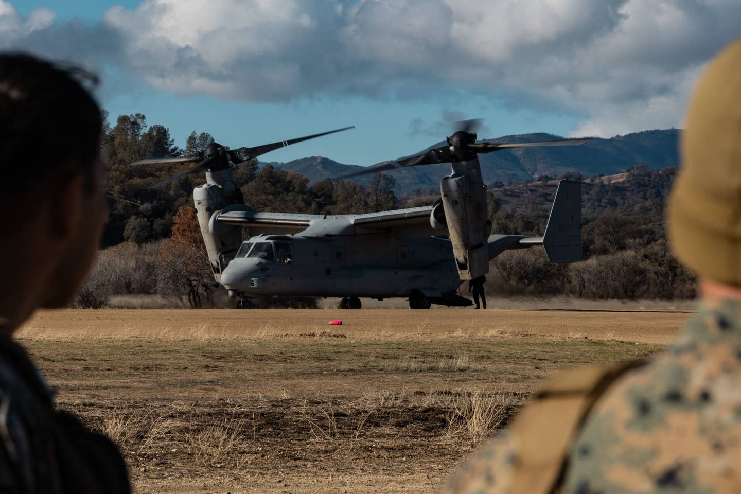 U.S. Marines with Marine Aircraft Group 39, 3rd Marine Aircraft Wing (MAW), guide the arrival of a MV-22B Osprey over radio during flight operations as part of Steel Knight 23 on Fort Hunter Liggett, Dec. 7, 2022. Exercise Steel Knight 23 provides 3d MAW an opportunity to refine Wing-level warfighting in support of I Marine Expeditionary Force and fleet maneuver. (U.S. Marine Corps photo by Lance Cpl. Shannon Gibson)