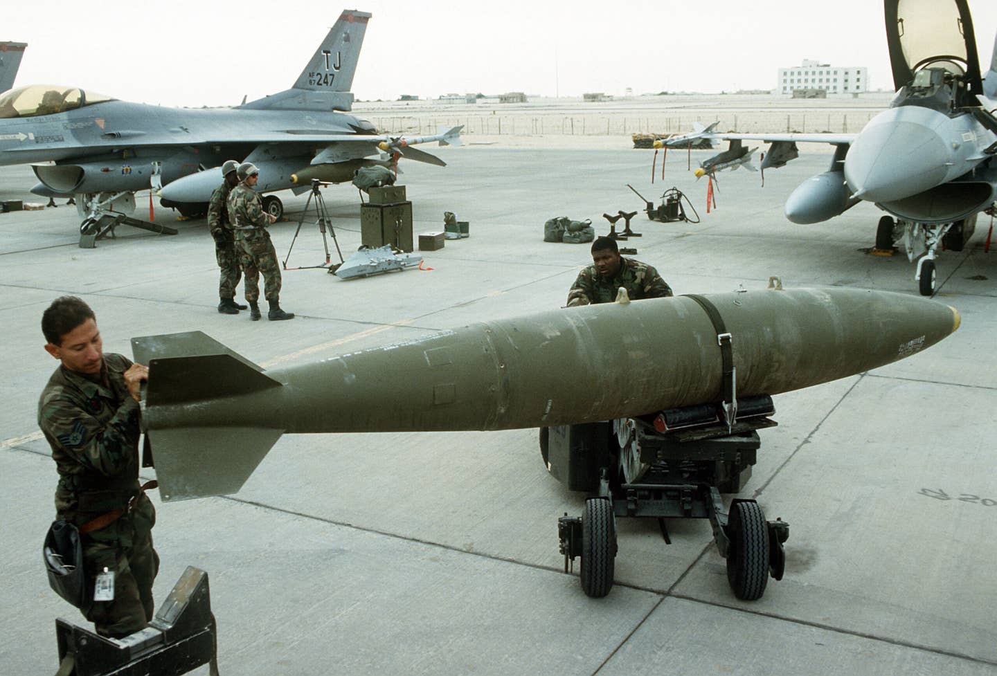 Preparation for loading 2,000-pound Mk 84 bombs onto F-16 aircraft for a daylight strike against Iraqi targets during Operation Desert Storm. The Mk 84 bomb body was used as the basis for the GBU-36/B GAM. <em>U.S. Air Force photo by SSgt. Lee F. Corkran</em>