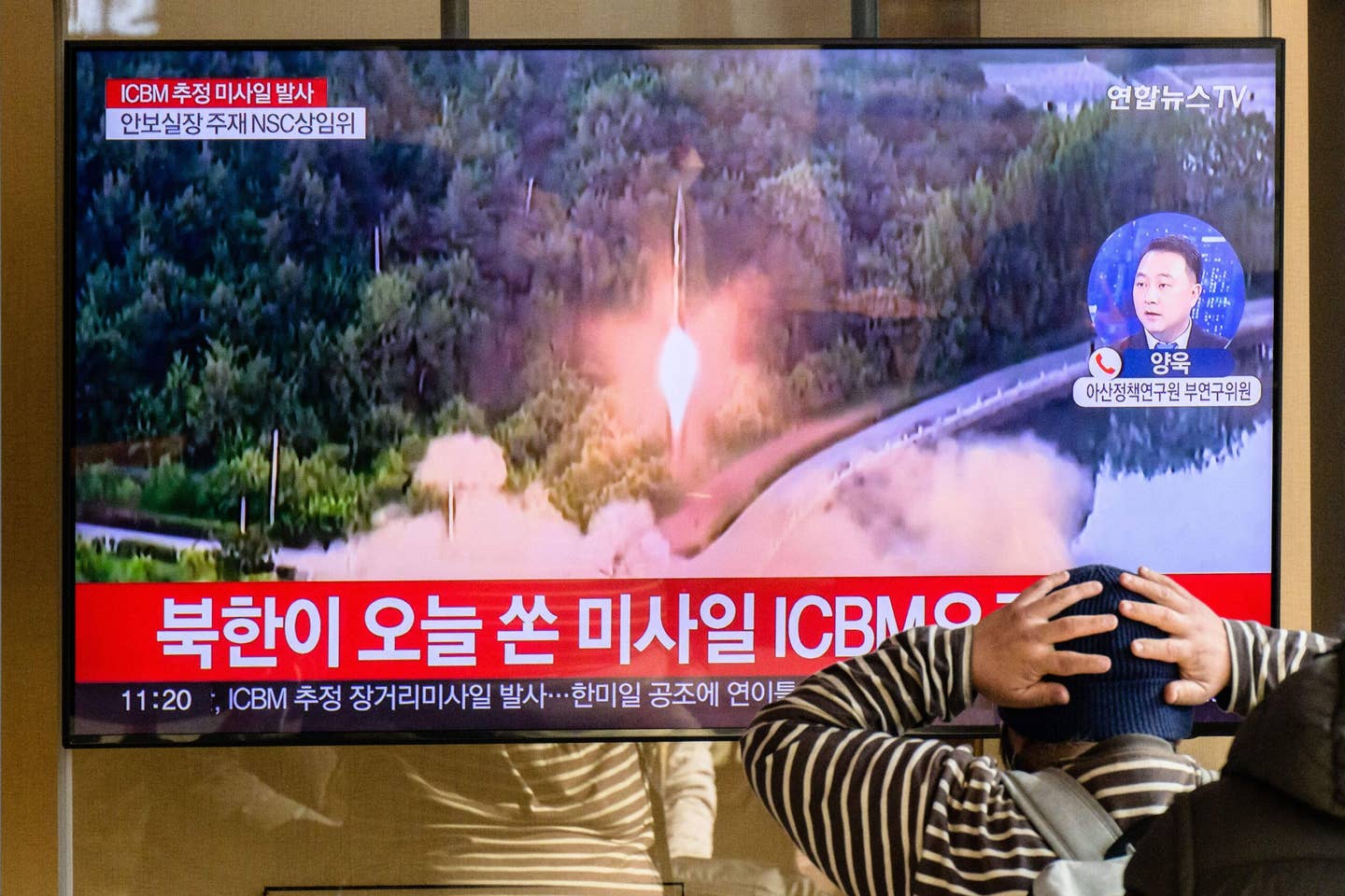 A man watches a television showing a news broadcast with file footage of a North Korean missile test, at a railway station in Seoul on November 18, 2022. <em>Credit: ANTHONY WALLACE/AFP via Getty Images</em>