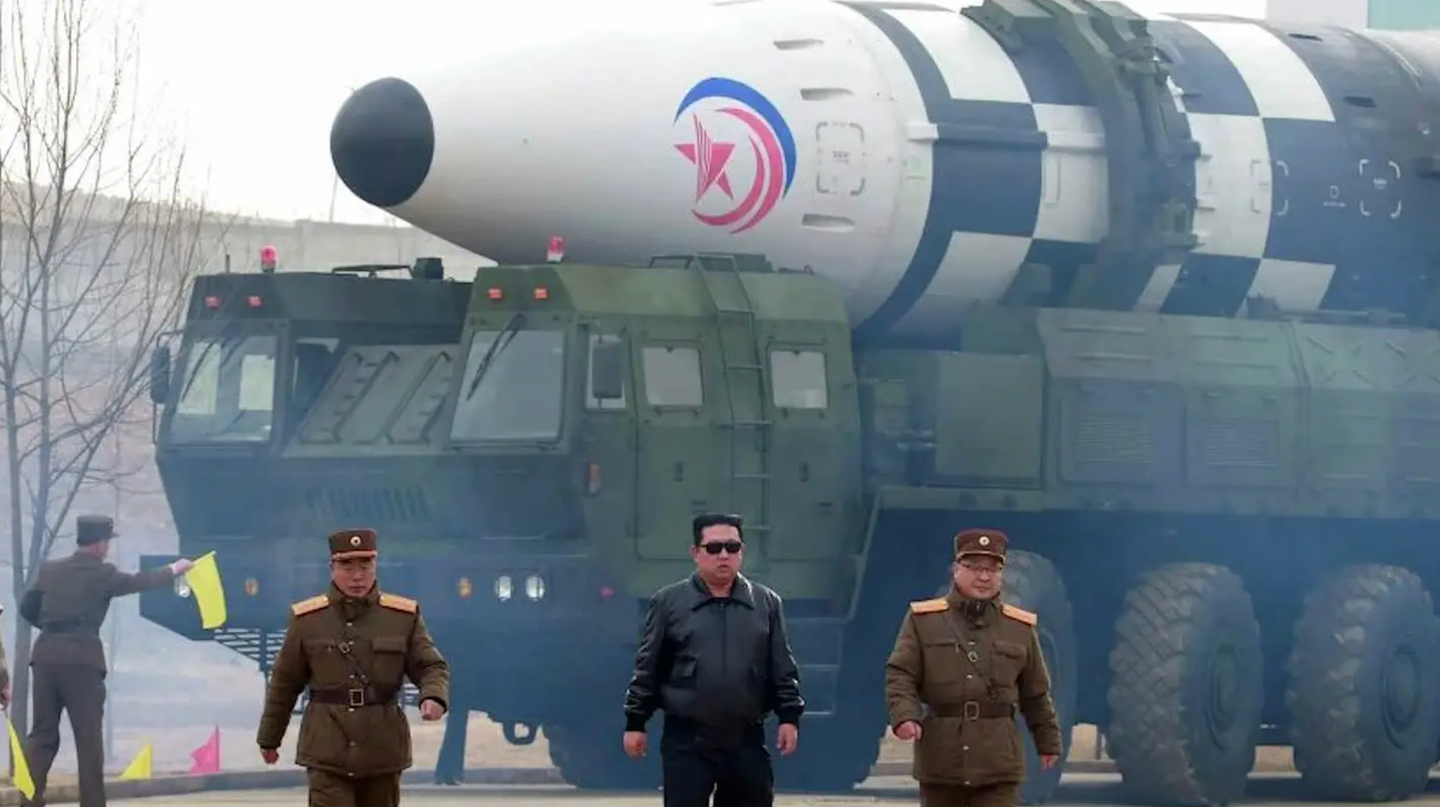 North Korean leader Kim Jong Un, in the black leather jacket and sunglasses at center, walks in front of a Hwasong-17 intercontinental ballistic missile on its transporter erector launch prior to a test on March 24, 2022. <em>North Korean state media</em>
