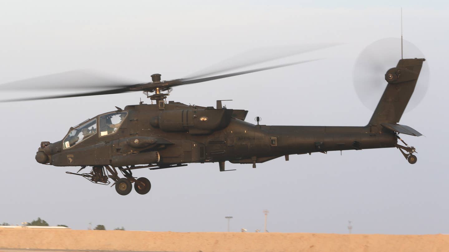 An AH-64E Apache assigned to 1st Battalion, 101st Aviation Regiment, takes off from the Udairi Landing Zone in Camp Buehring in Kuwait in October 2022. A sponson fitted with distinctive components of the CIRCM system is seen fitted to the tip of its left stub wing. <em>Army National Guard</em>