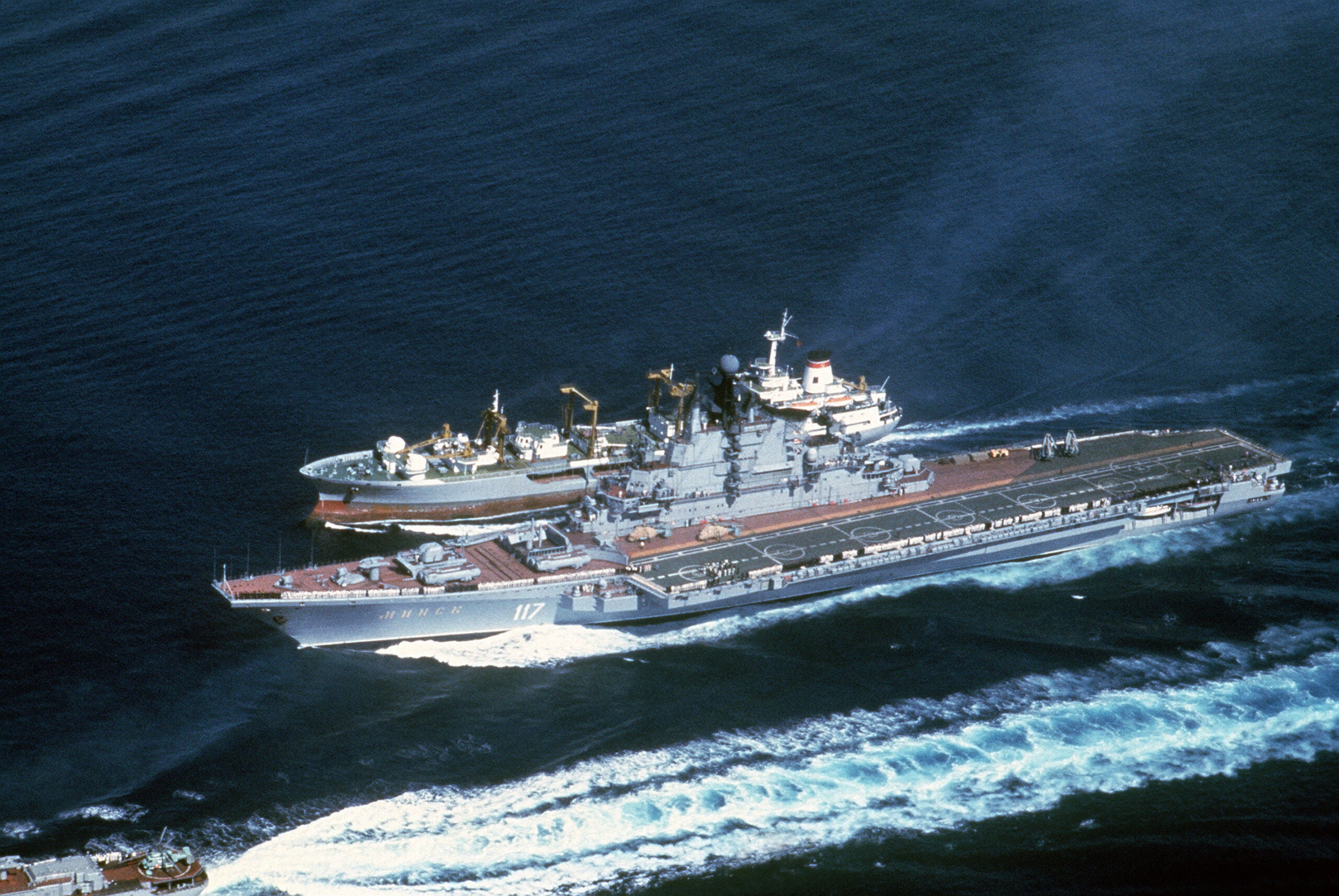 An aerial port bow view of the Soviet aircraft carrier MINSK (CVHG), center, and a Boris Chilikin class oiler during an underway replenishment.