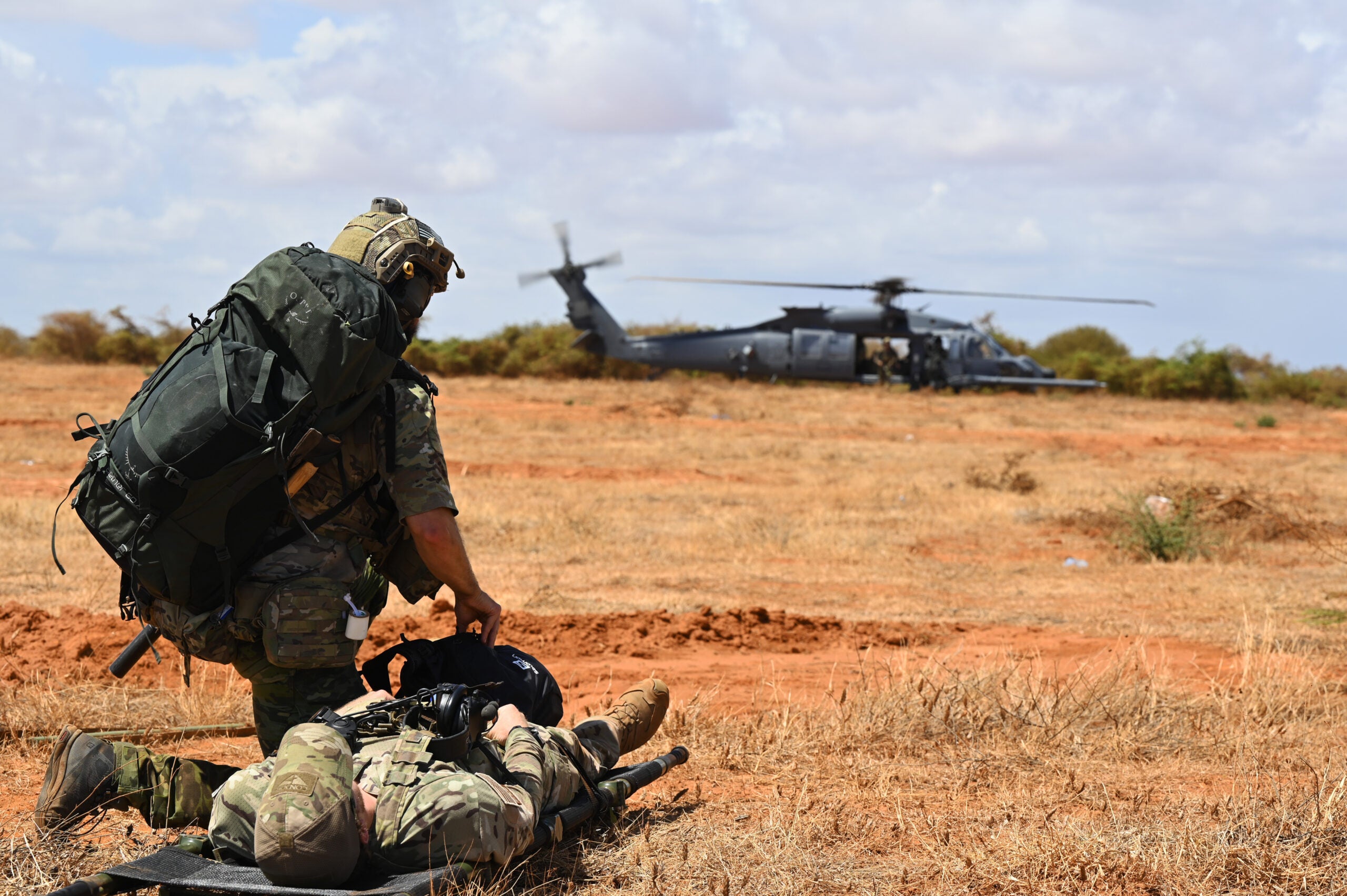 A U.S. Pararescueman prepares to move a simulated casualty to a HH-60W combat rescue helicopter during a casualty evacuation (CASEVAC) exercise while his teammates secure the perimeter at an undisclosed Combined Joint Task Force-Horn of Africa area of responsibility, Dec 8, 2022. Conducting CASEVAC exercises prepares rescue personnel for any humanitarian or crisis response scenario, regardless of the time and place, as well as the availability of stable medical facilities. (U.S. Air Force photo by Tech. Sgt. Jayson Burns)