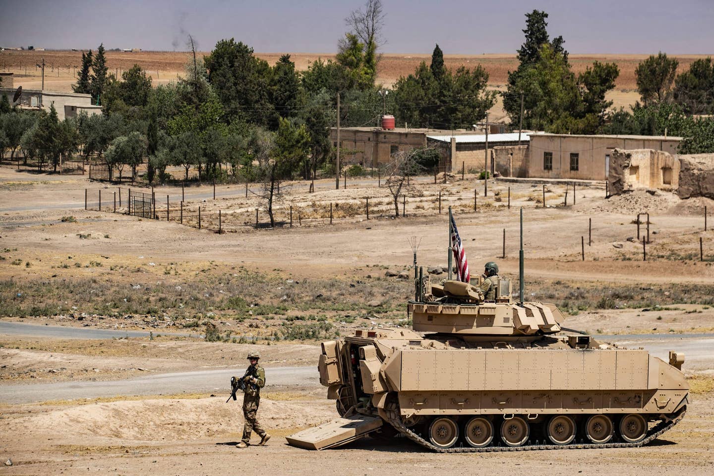 A US soldier walks out of a Bradley Fighting Vehicle (BFV) equipped with BRAT tiles during a patrol near the Rumaylan (Rmeilan) oil wells northeast Syria on June 22, 2021. (Delil SOULEIMAN / AFP)
