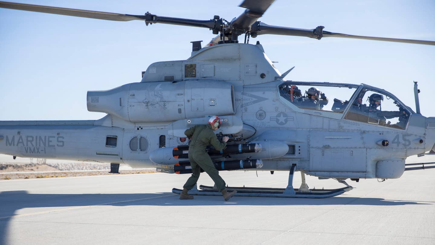 A U.S. Marine with Marine Operational Test and Evaluation Squadron One (VMX-1) arms a JAGM on an AH-1Z before takeoff at Marine Corps Air Station Yuma, Arizona, in December 2021. <em>U.S. Marine Corps photo by Cpl. Matthew Romonoyske-Bean</em>
