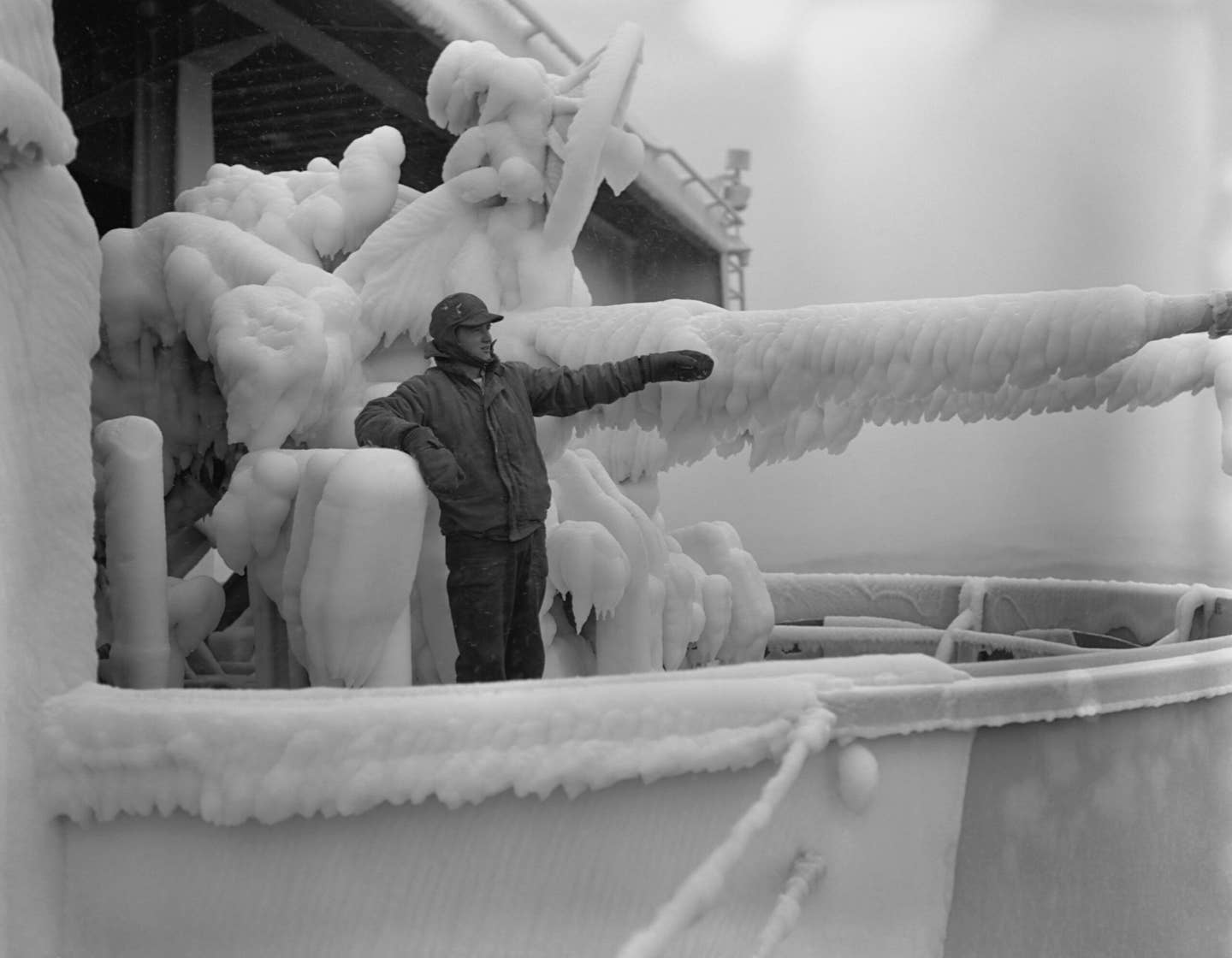 A gun captain on a mount aboard the aircraft carrier USS <em>Oriskany</em> inspects the thick layer of ice covering the gun, mount, and mechanism while cruising off Korea. <em>Photo by © CORBIS/Corbis via Getty Images</em>