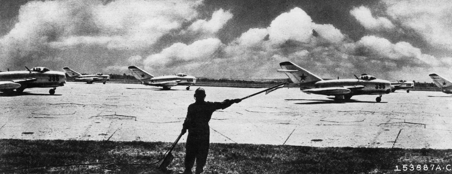 A flight of Soviet MiG-15 jet fighters prepares to take off, under the direction of a field controller, sometime in the early 1950s. <em>National Museum of the U.S. Air Force</em><br>