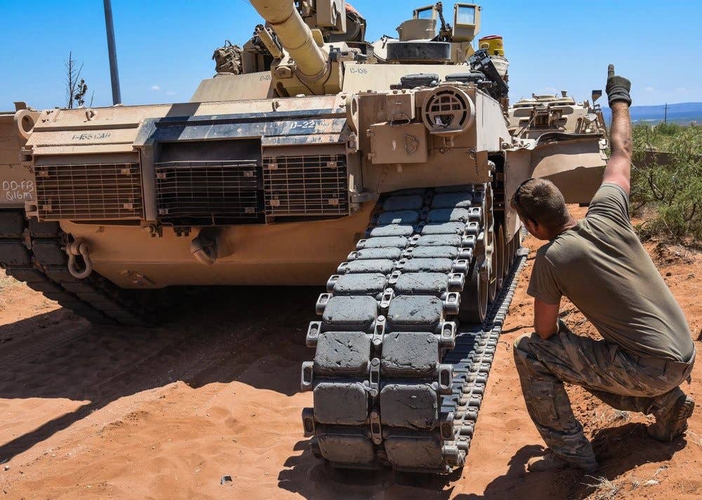 Spc. Derek Sparks, a track vehicle mechanic, with Company D, 106th Support Battalion, guides a M88 Recovery Vehicle as they pull the track back onto a M1A1 Abrams Tank near Oro Grande N.M. (U.S. Army National Guard photo by Sgt. Brittany Johnson.)