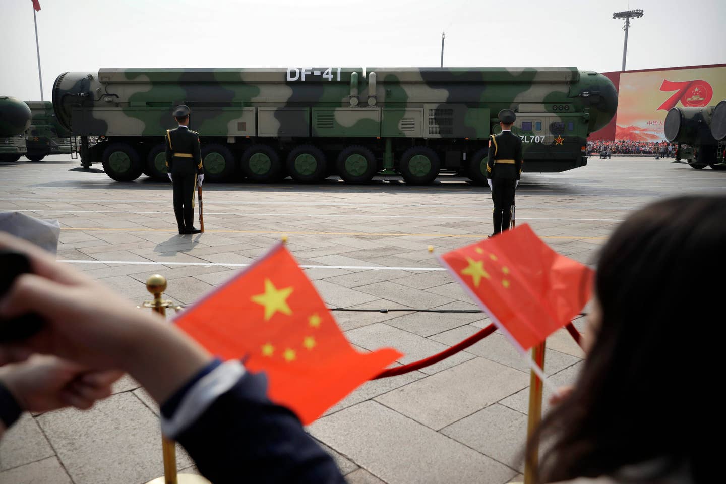 Spectators wave Chinese flags as military vehicles carrying DF-41 ICBMs roll during a parade to commemorate the 70th anniversary of the founding of Communist China in Beijing on Oct. 1, 2019. <em>Credit: AP Photo/Mark Schiefelbein</em>