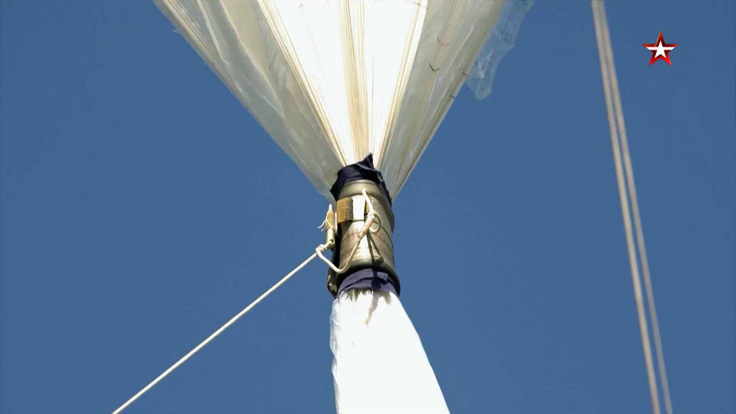 Clamps on the uninflated part of the balloon envelope serve to reduce the effects of wind; the balloon can take off in winds up to 22 miles per hour. As the balloon fills up, these clamps fall off. <em>TV Zvezda</em>