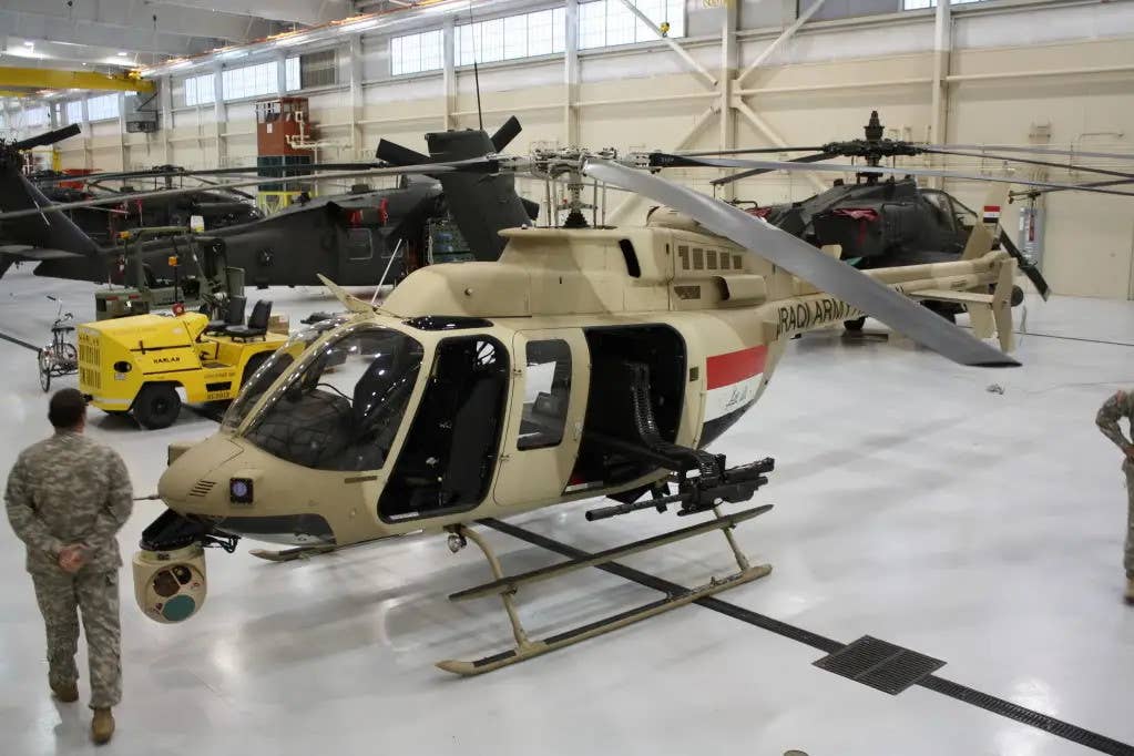 An Iraqi Army IA-407 helicopter in a hangar alongside various U.S. Army helicopters ahead of delivery. <em>DOD</em>