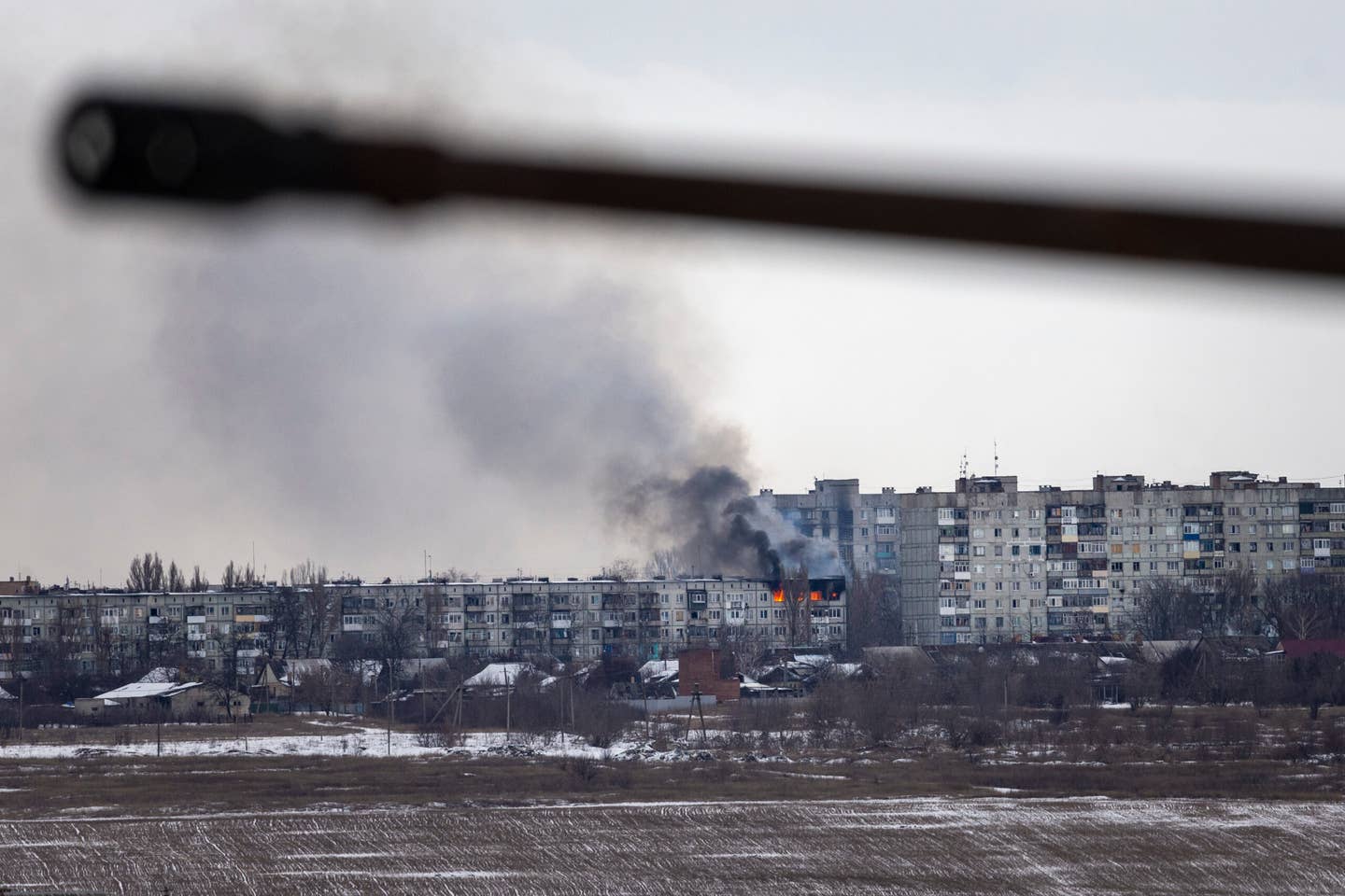 A Ukrainian military vehicle drives by as an apartment building hit by Russian artillery burns in the distance on Feb. 14, 2023 in Bakhmut. (Photo by John Moore/Getty Images)