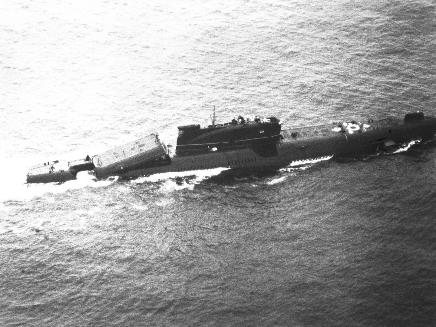An elevated starboard beam view of a Soviet <em>Juliett</em> class cruise missile submarine underway with one of its missile launchers in a raised position. <em>DVIDS and NARA</em>