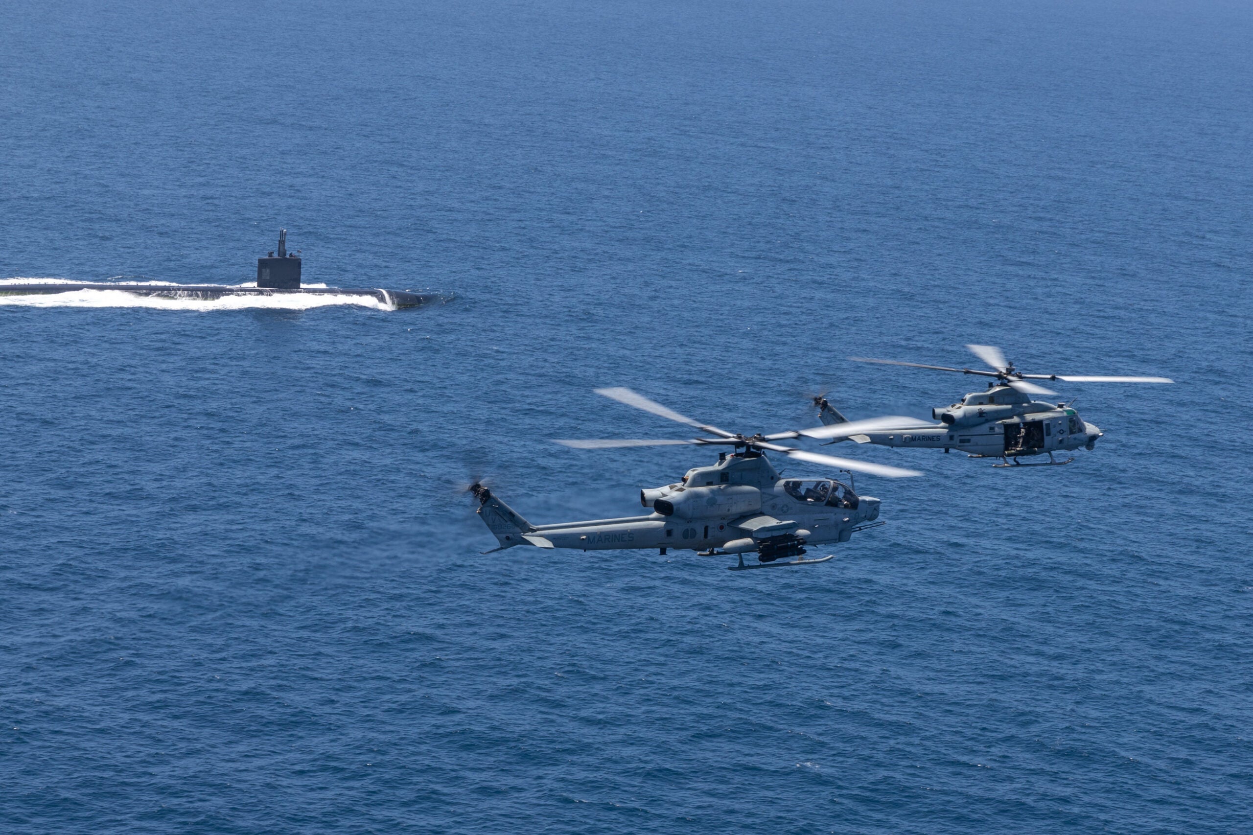 U.S. Marine Corps AH-1Z Viper and UH-1Y Venom with Marine Light Attack Helicopter Squadron 267, Marine Aircraft Group 16, 3rd Marine Aircraft Wing (MAW), fly over a U.S. Navy Submarine during Advanced Naval Basing evolution of Summer Fury 21 at San Clemente, California, July 20, 2021. Advanced Naval Basing offering forward logistics and support, as well as sensor and strike capabilities that make a significant contribution to undersea warfare campaigns in the Indo-Pacific region. Summer Fury is an exercise conducted by 3rd MAW in order to maintain and build capability, strength and trust within its units to generate the readiness and lethality needed to deter and defeat adversaries during combat operations as the U.S. Marine Corps refines tactics and equipment in accordance with Force Design 2030. (U.S. Marine Corps photo by Lance Cpl. Isaac Velasco)