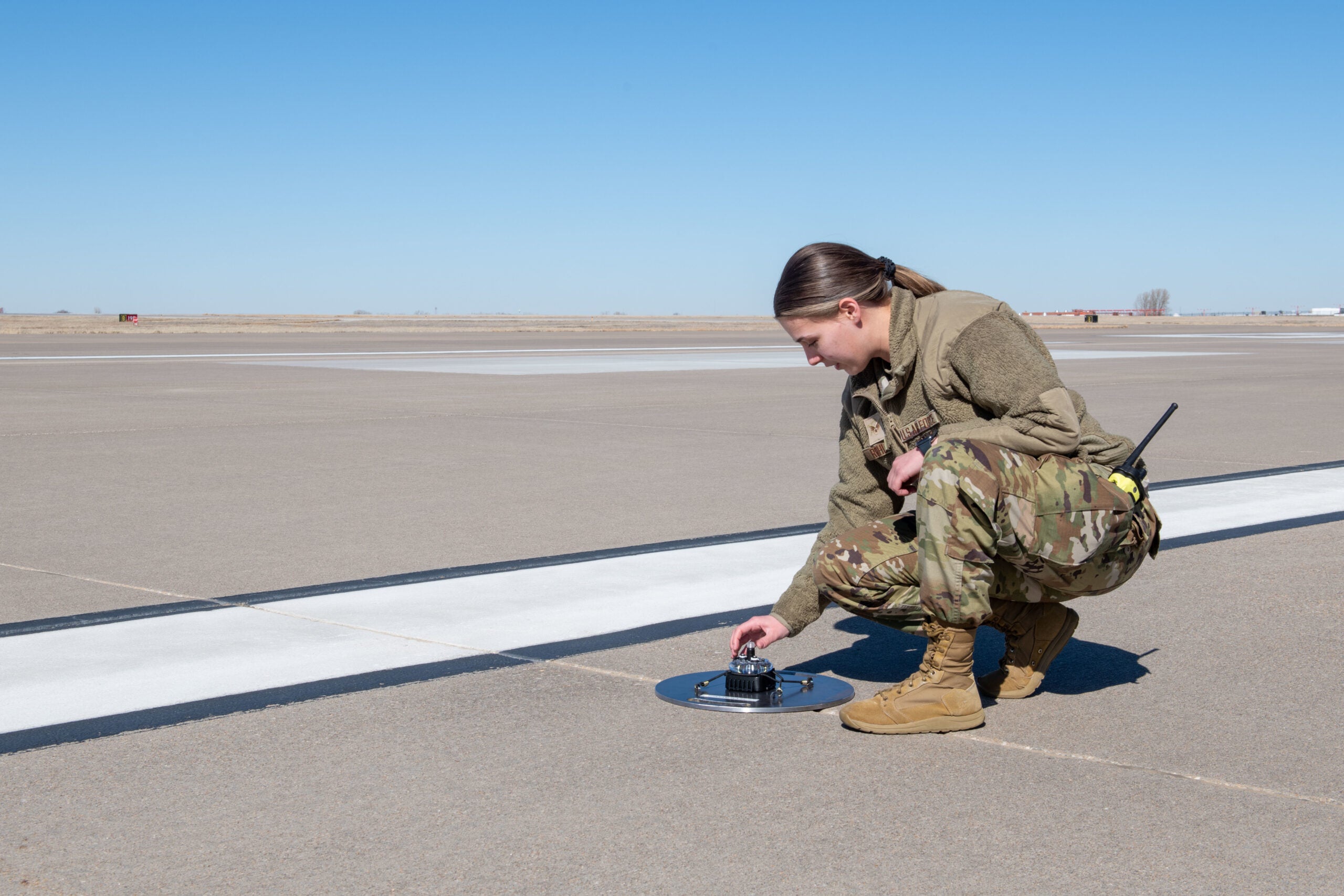 Senior Airman Genavieve Rohling, 22nd Operations Support Squadron, airfield management shift lead, places a Phantom ALZ-15 portable landing zone light on the runway in preparation for Airfield Marking Patterns (AMP)-3 system training at McConnell Air Force Base, Kansas, Feb. 17, 2023. AMP-3 is a standard set of marking used to identify runways and other areas of an airport or landing zones. (U.S. Air Force photo by Staff Sgt. Adam Goodly)